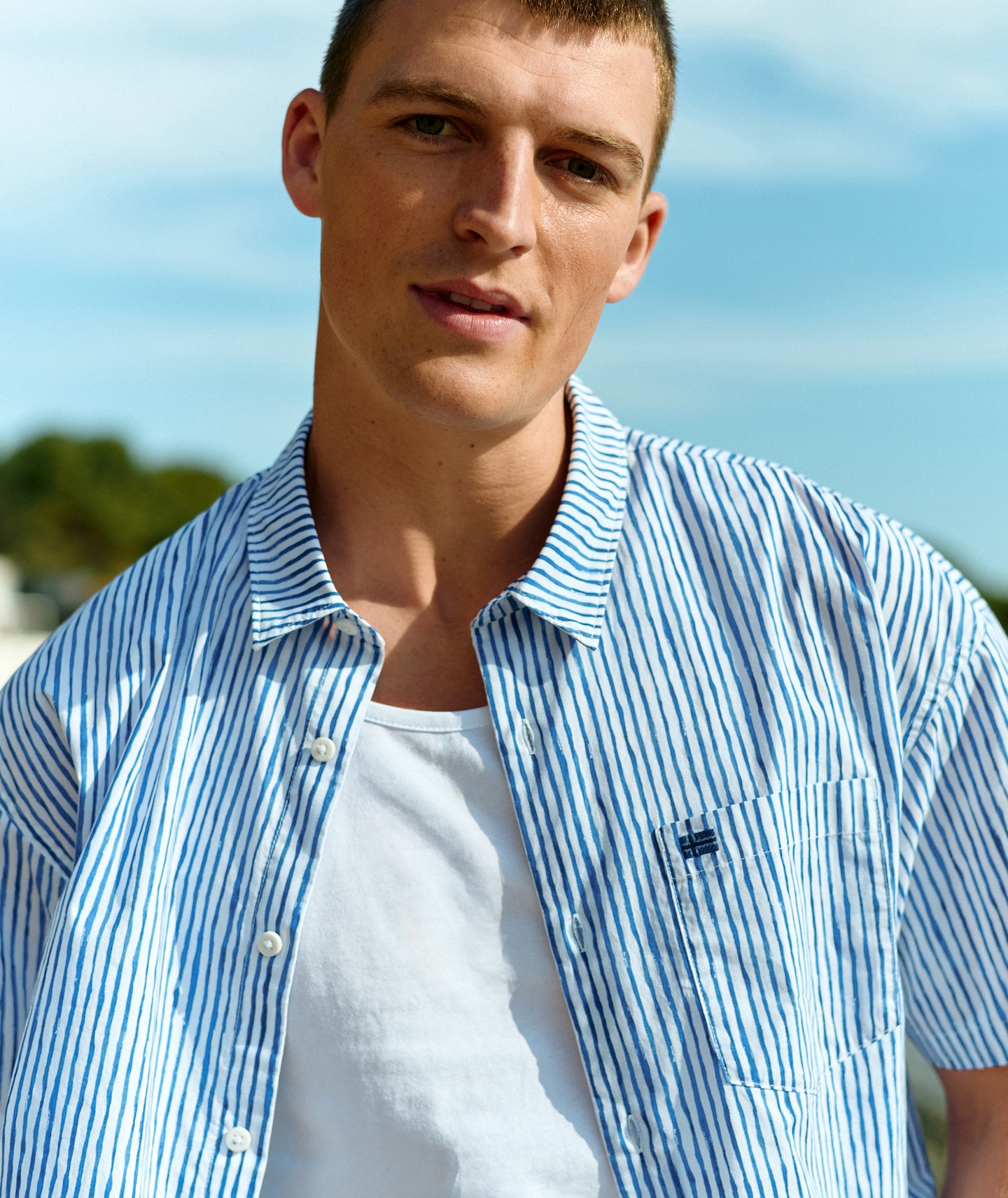 Model wears Tommy Jeans blue and white stripe shirt.