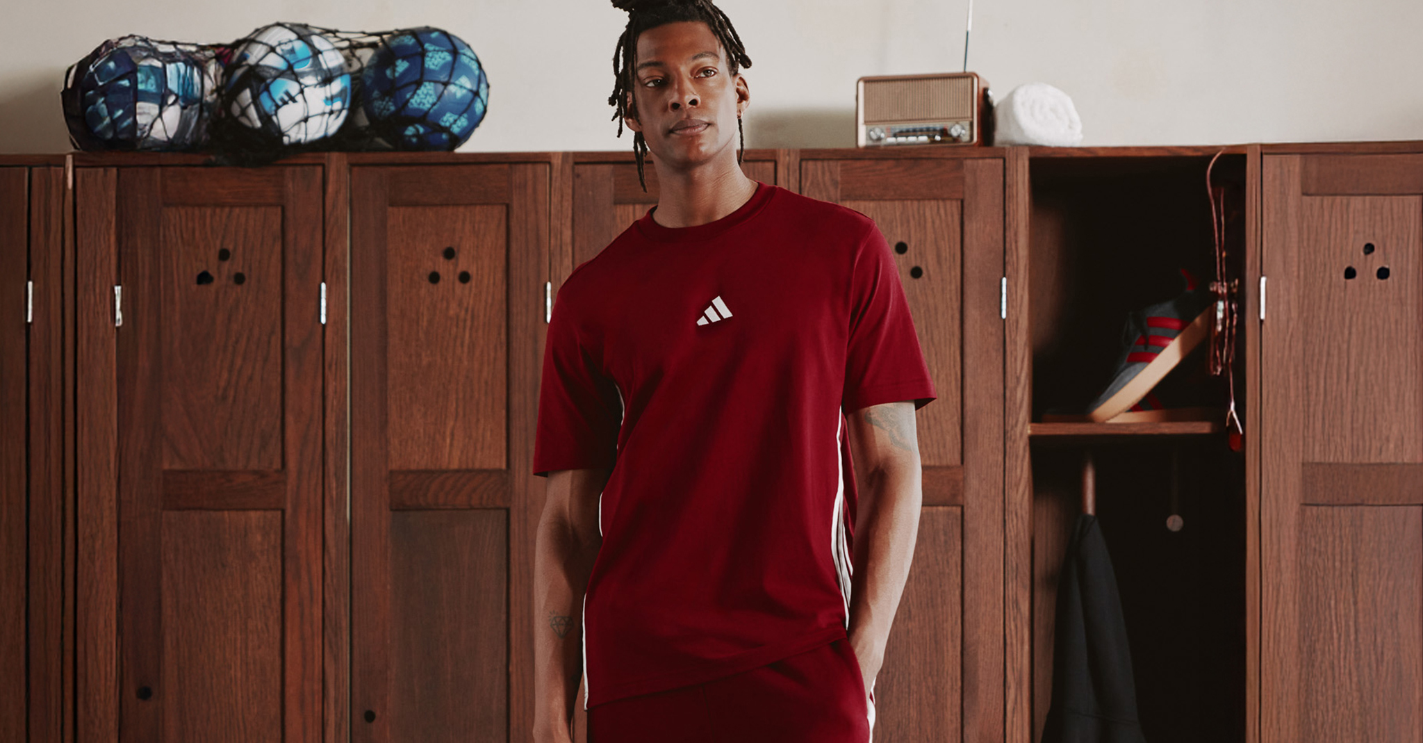 Summer of Sport. Model pictured with sports lockers wears adidas 3 Stripes T-Shirt with adidas Wide Leg 3 Stripes Fleece Pants