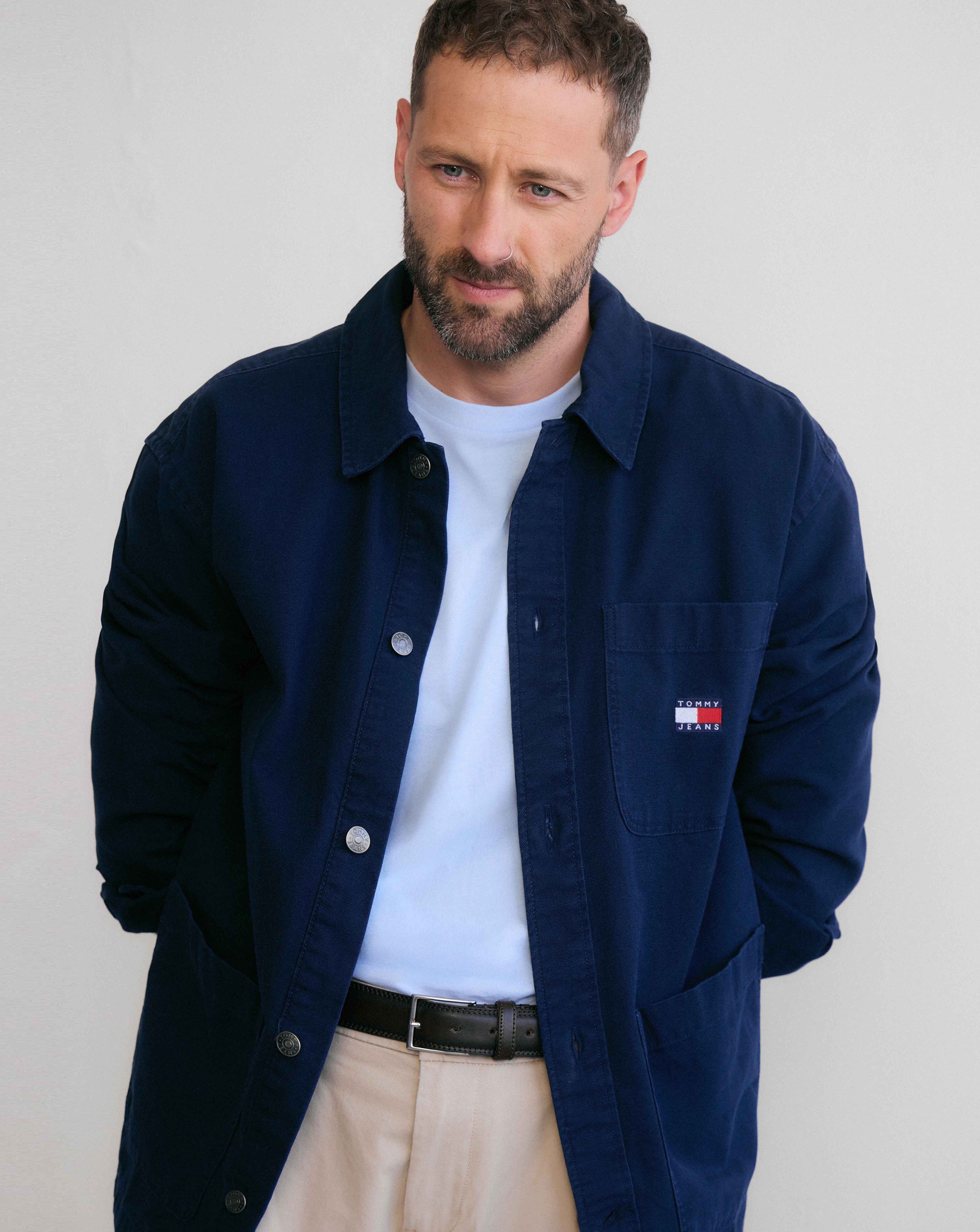 Model is wearing a blue Tommy Hilfiger short sleeve t-shirt underneath a navy Tommy Hilfiger shirt.