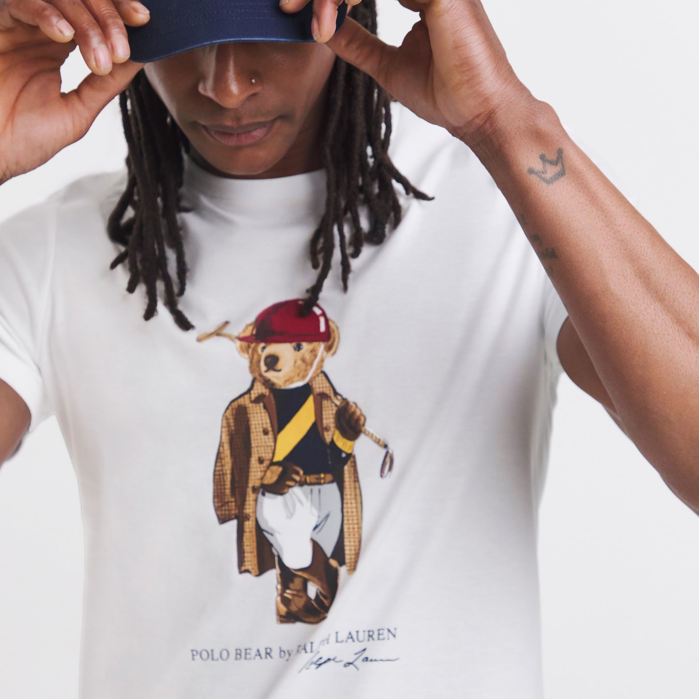 Model is wearing a white Polo Ralph Lauren short sleeve bear print t-shirt with a navy cap.