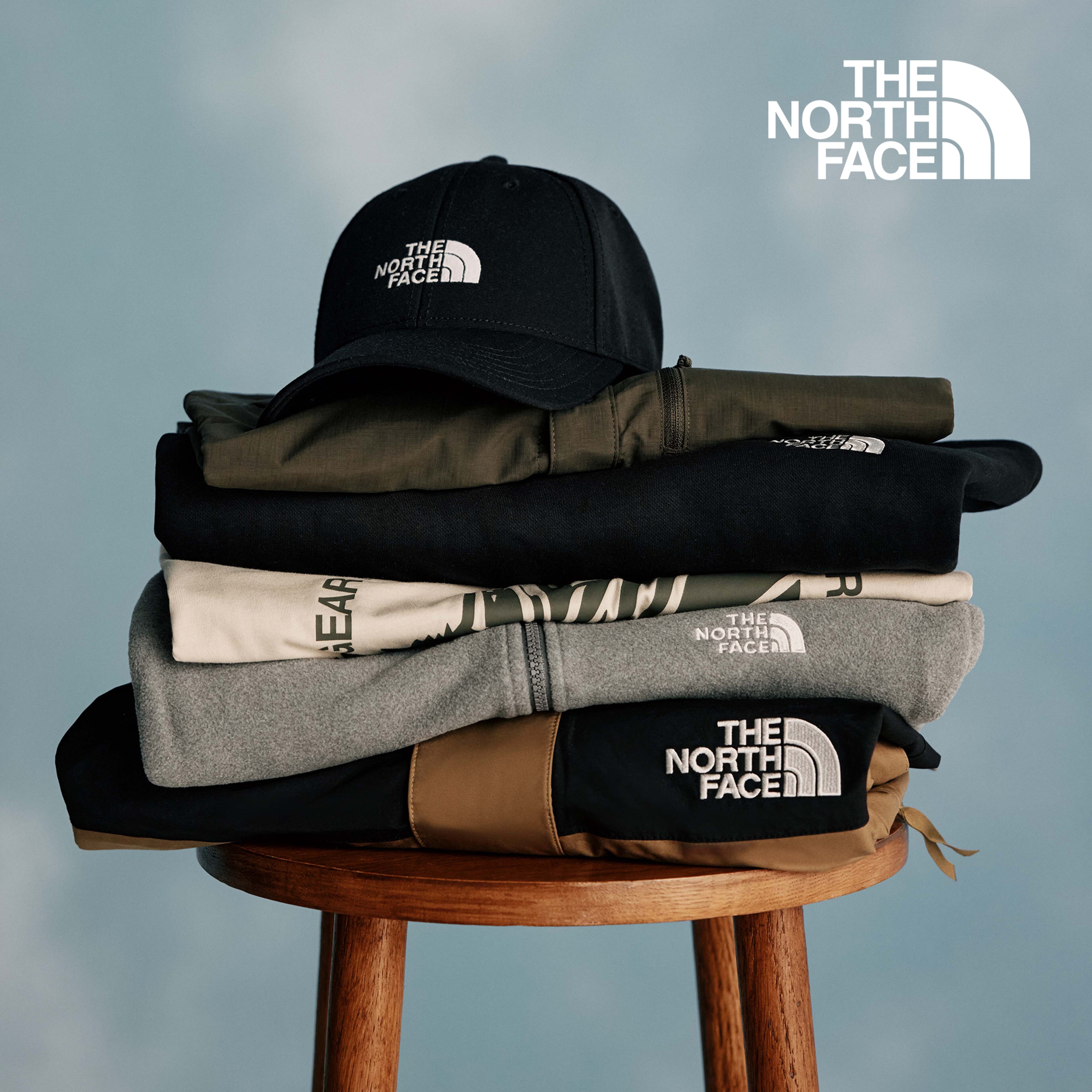 The North Face. Clothing from The North Face folded up on a stool including The North Face Monte Regular T-Shirt