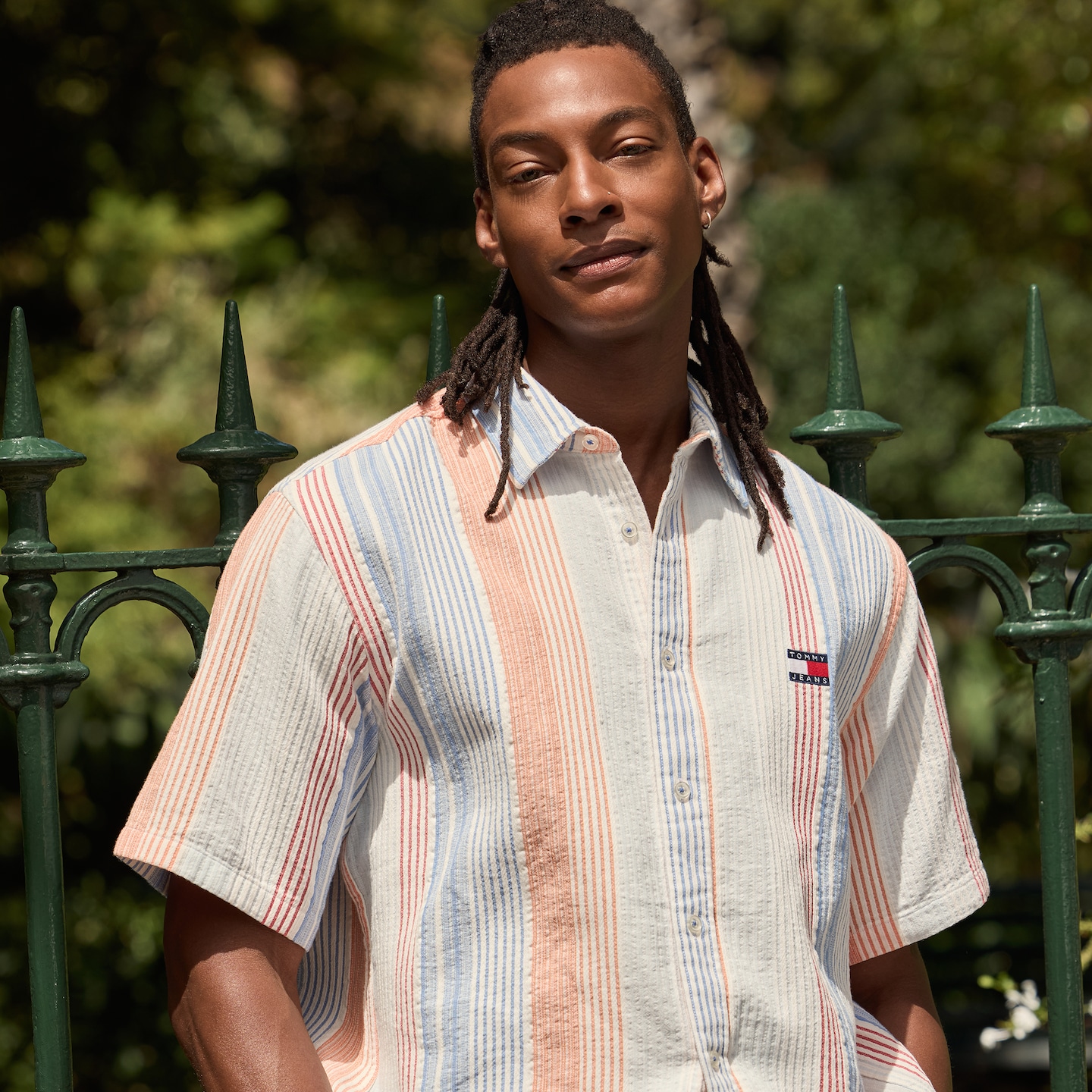 Model is wearing a white stripe Tommy Jeans short sleeve relax shirt with matching shorts.