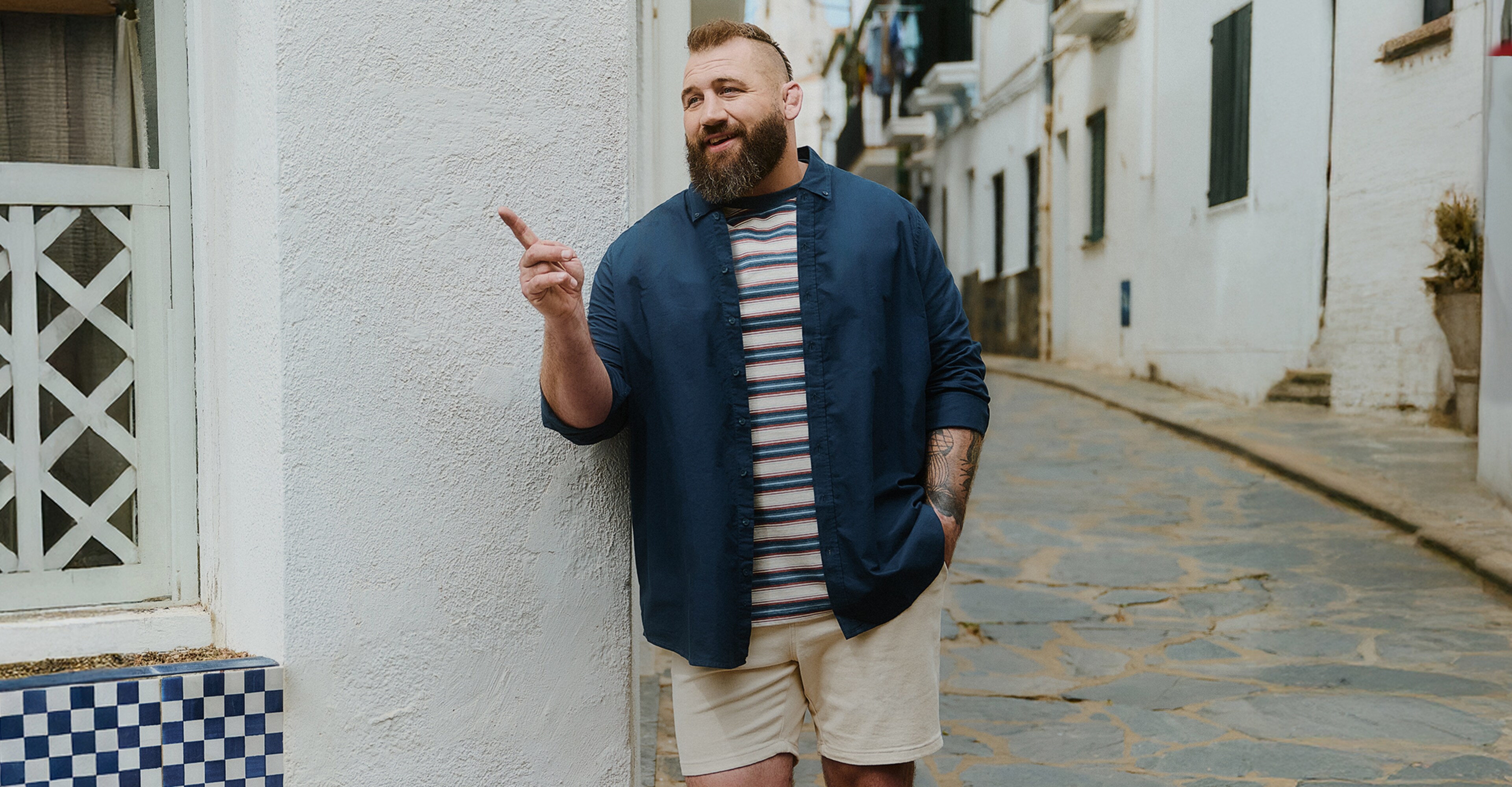 Joe Marler wears Union Relaxed Fit Marl Yarn Dye Stripe T-Shirt Long with Navy shirt and cream shorts