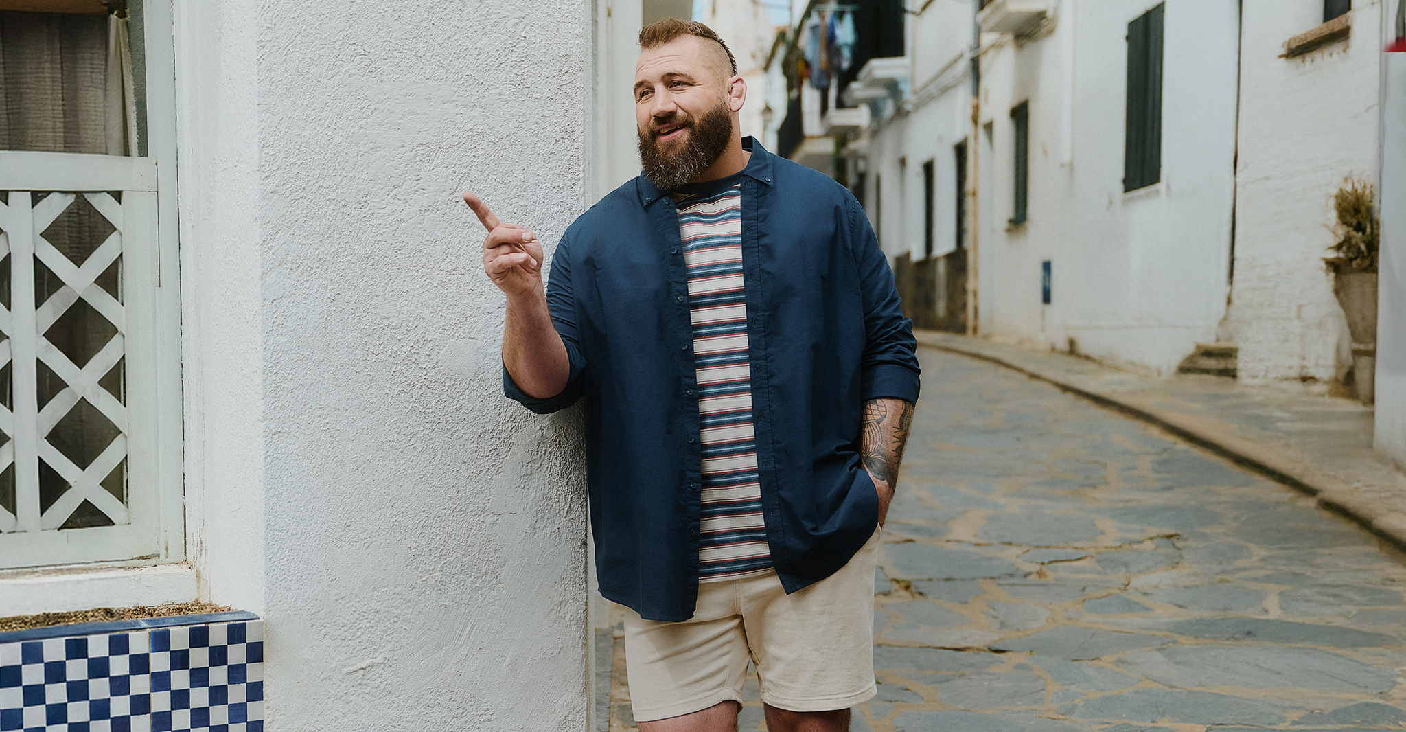 Joe Marler wears Union Relaxed Fit Marl Yarn Dye Stripe T-Shirt Long with Navy shirt and cream shorts
