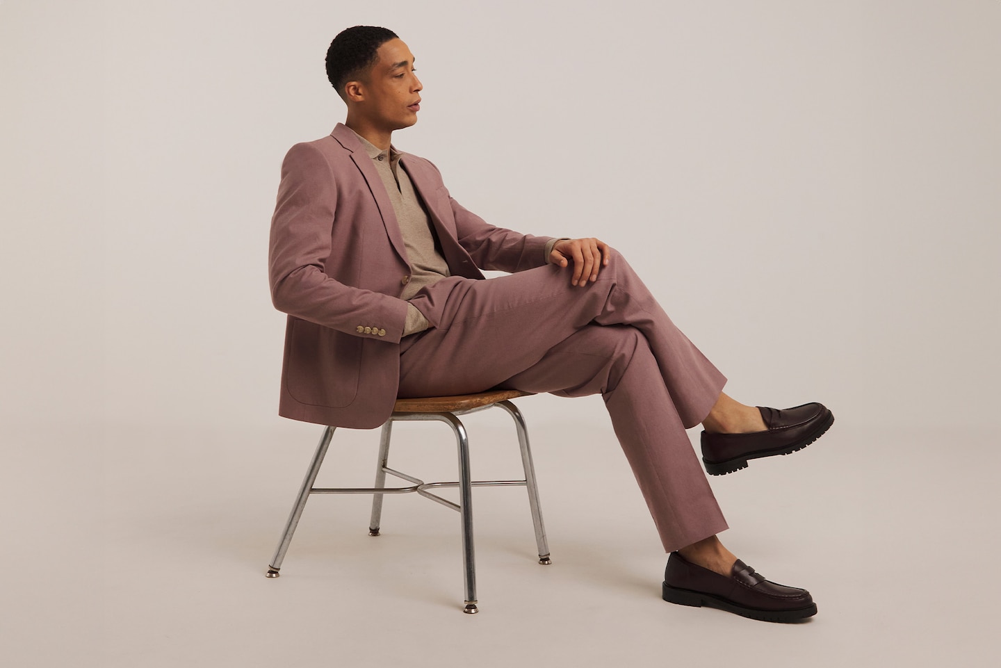 Model sat on chair wearing full piece pink suit and loafers