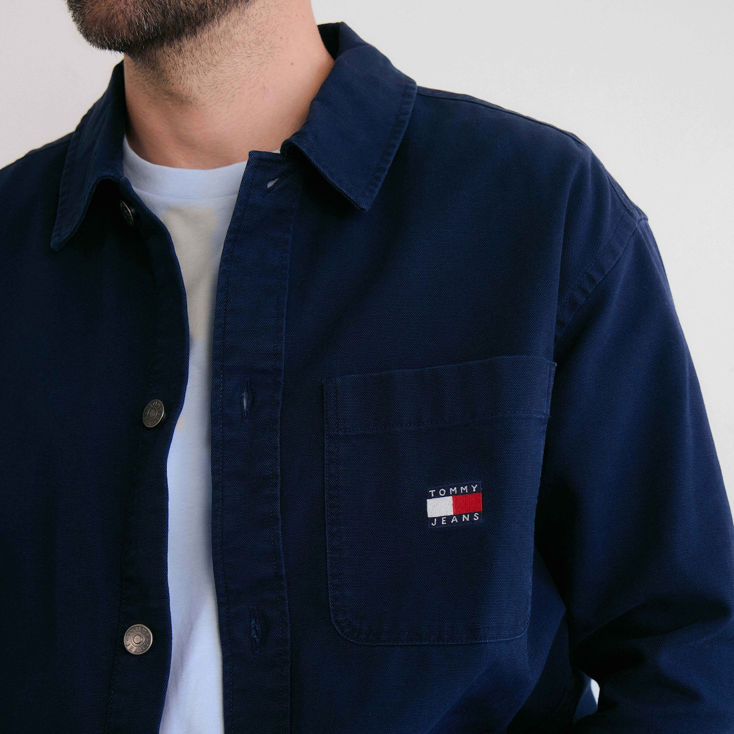 Model is wearing a navy Tommy Hilfiger shirt over a light blue Tommy Hilfiger short sleeve t-shirt.