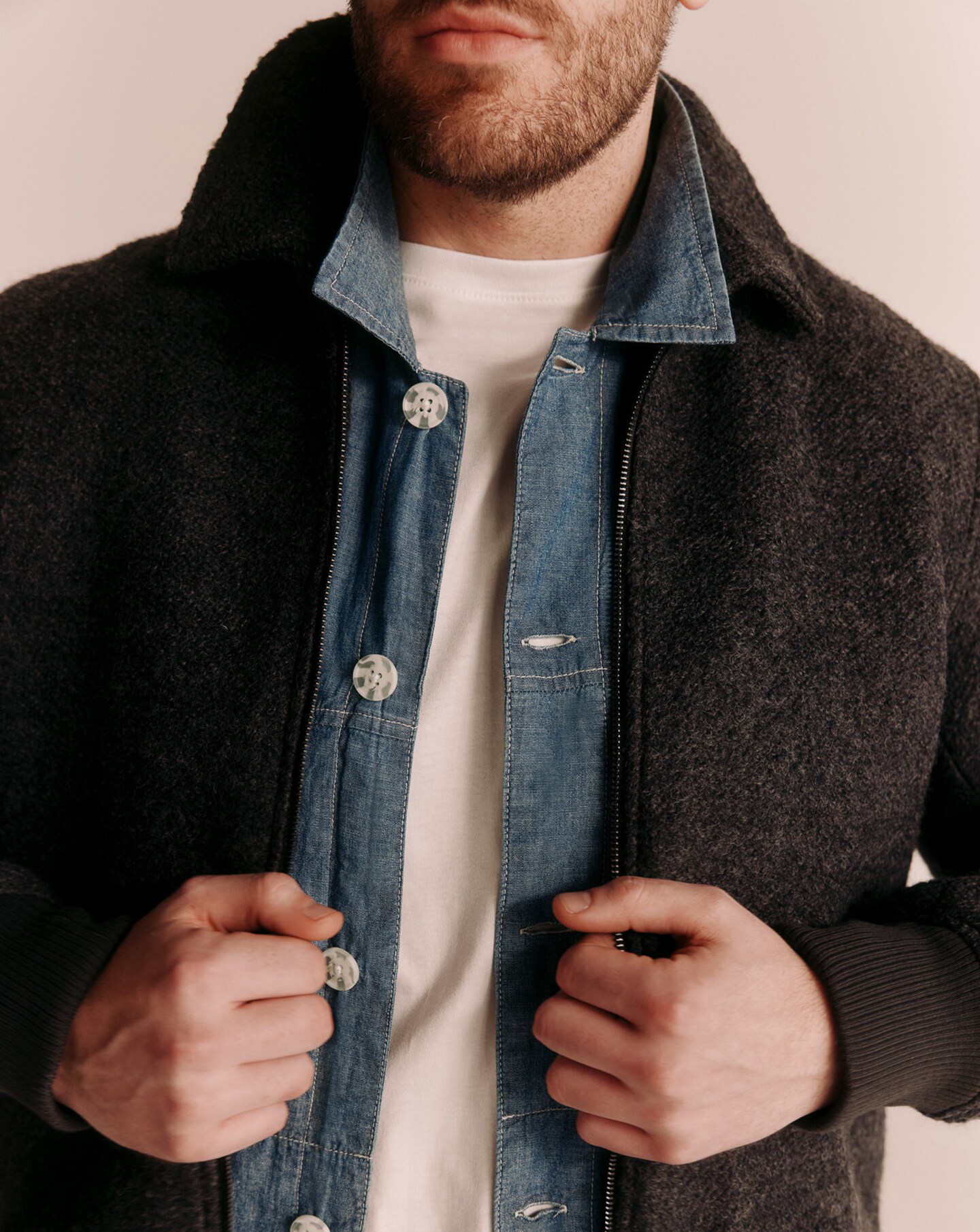 Model wearing a coat layered on top of a denim jacket and white t-shirt