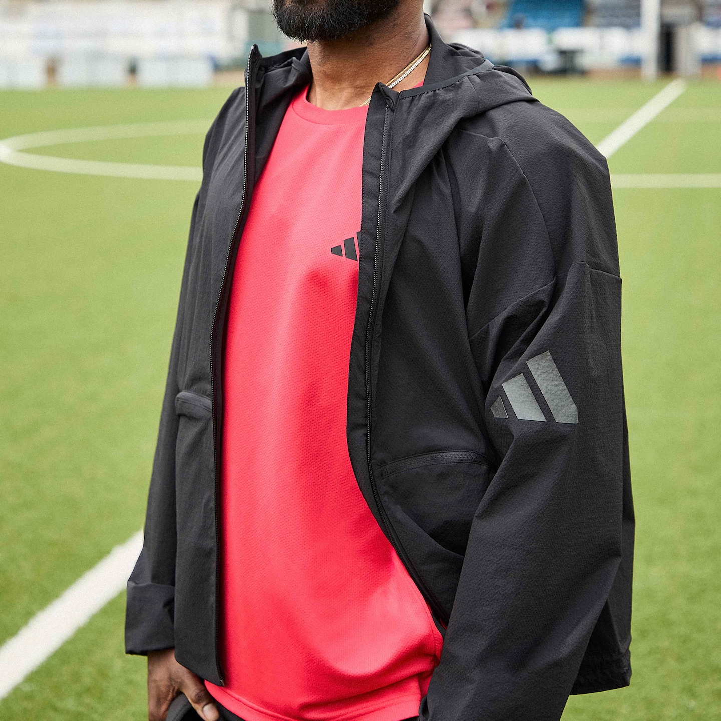 Model is wearing a red adidas workout training t-shirt under a black adidas jacket.