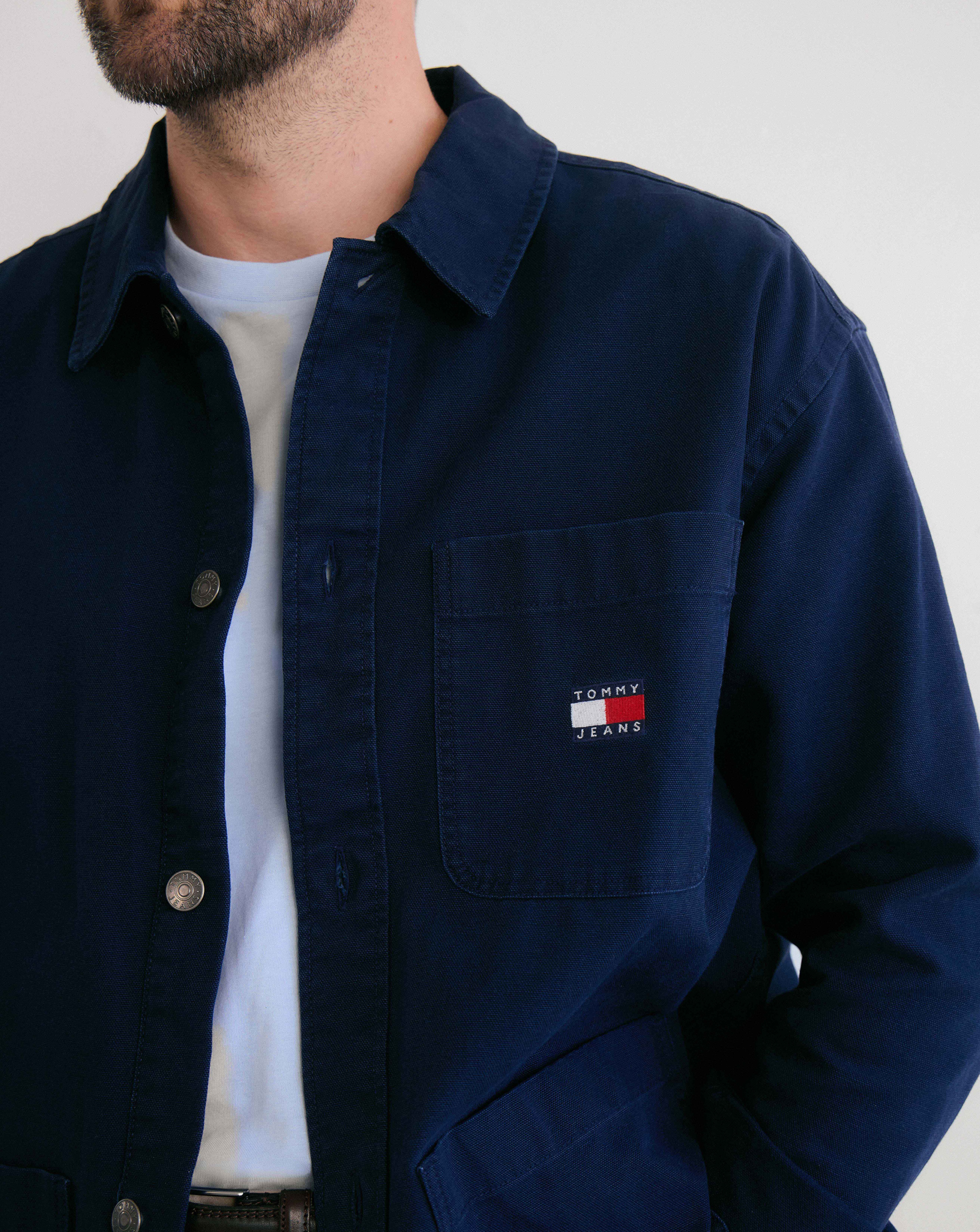 Model is wearing a Tommy Jeans essential overshirt in navy over a white t-shirt.
