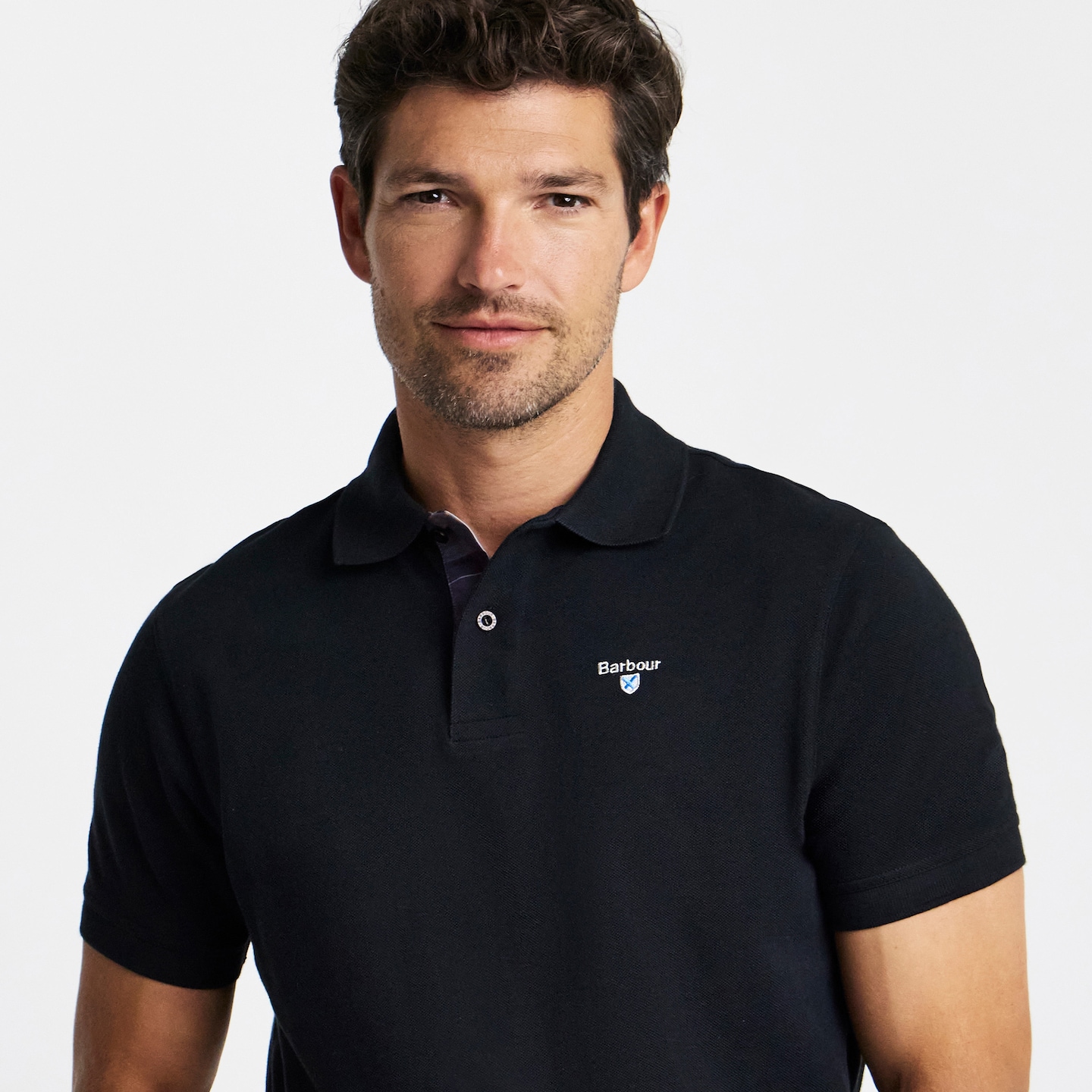 Model is wearing a black Barbour tartan trim pique polo.