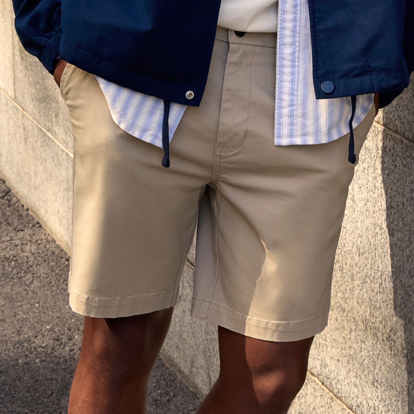 Model is wearing a pair of cream shorts.