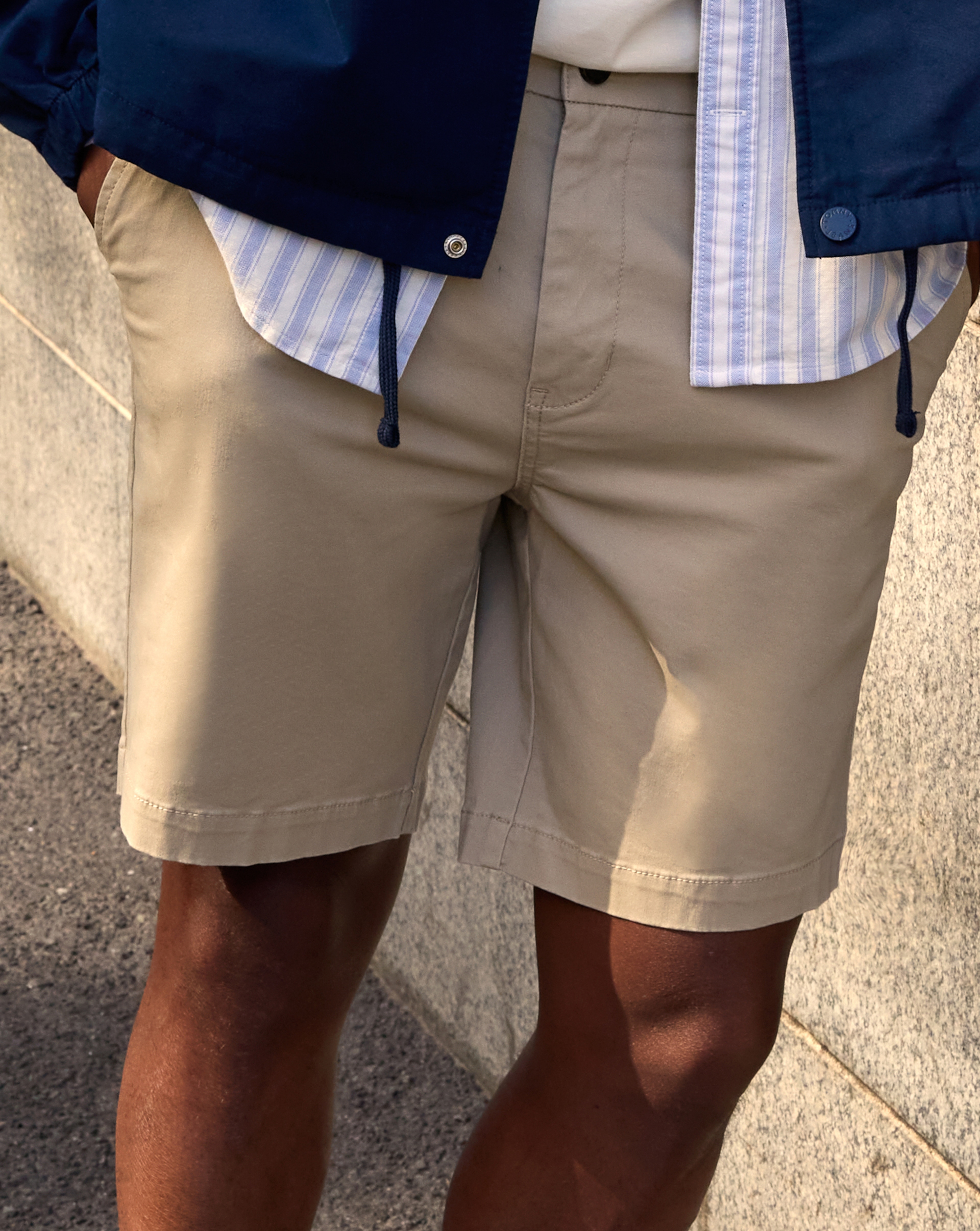 Model is wearing a pair of cream shorts.