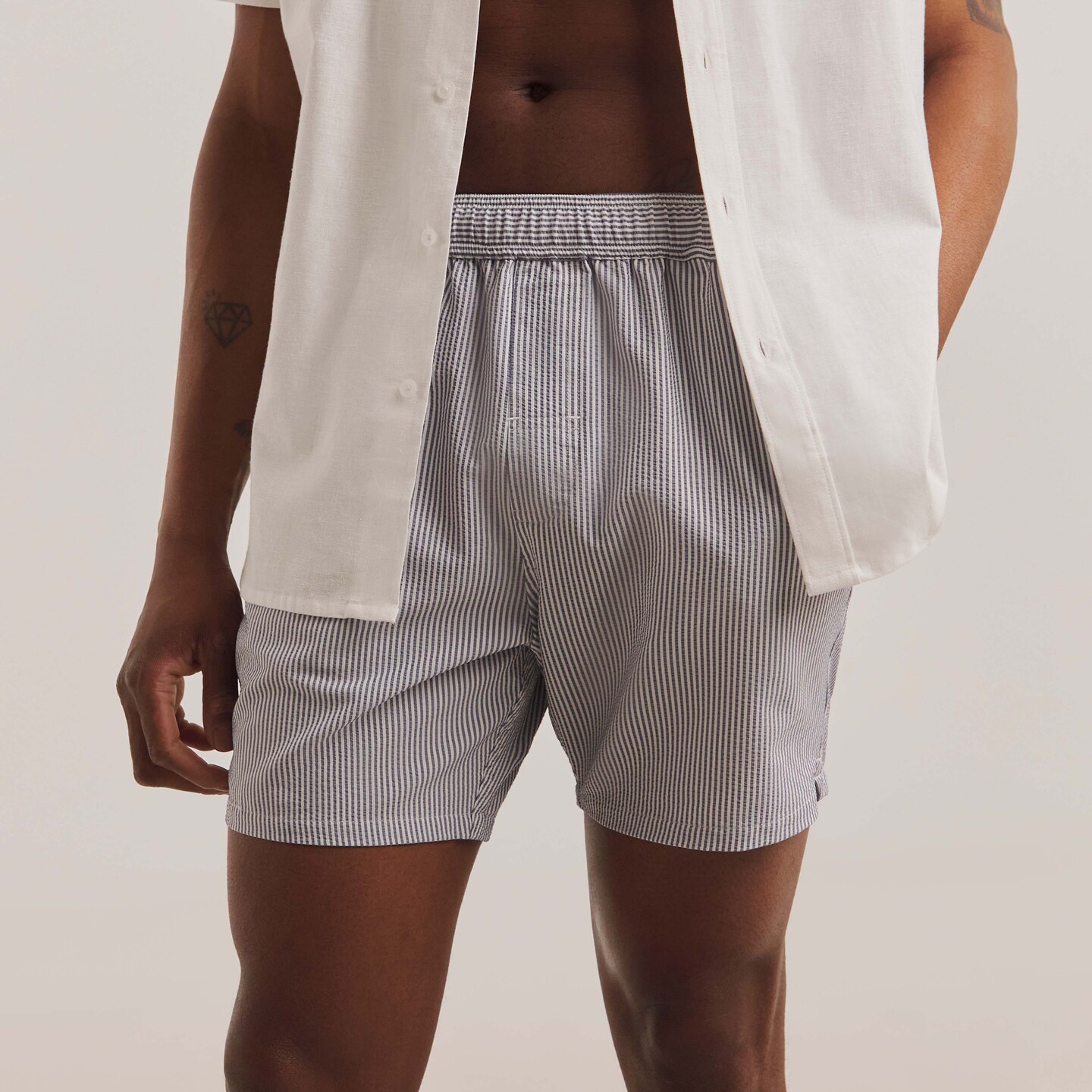 Model wears blue pin stripe swim shorts