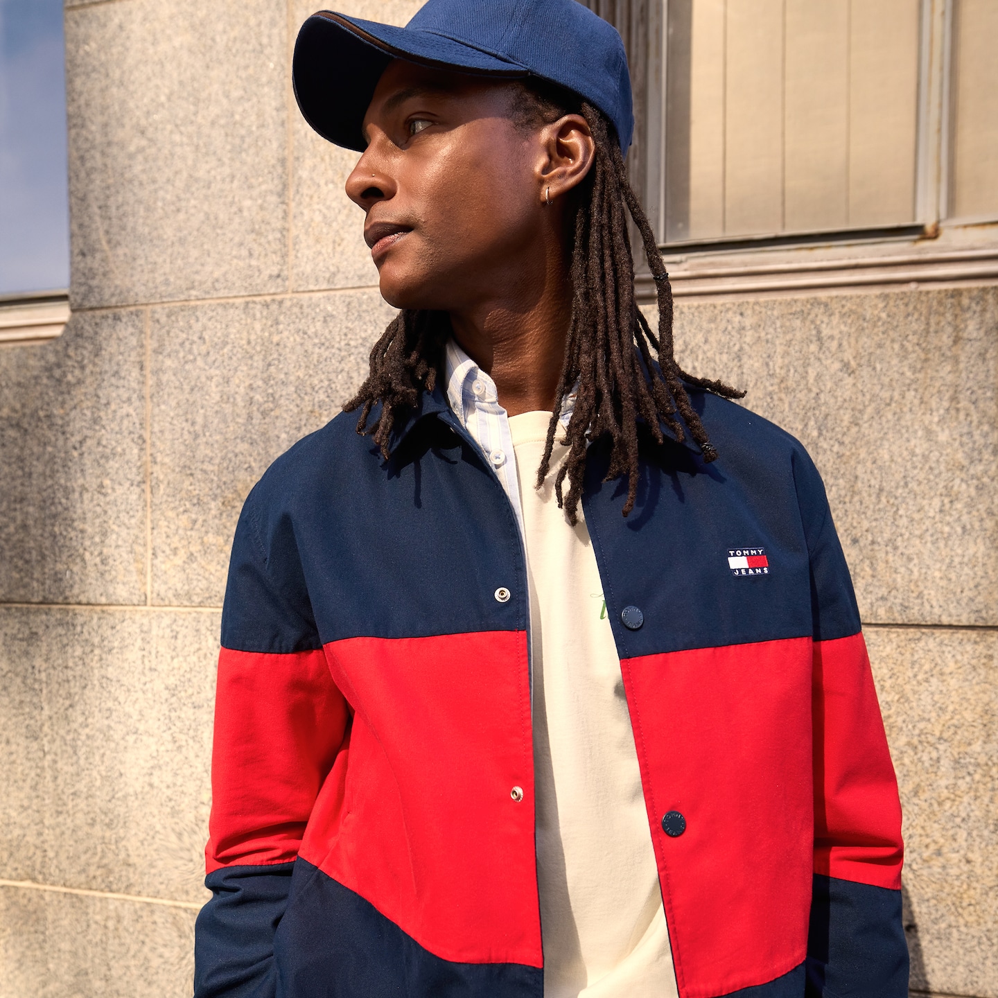 Model is wearing a navy and red Tommy Jeans Colorblock overshirt with a blue cap.