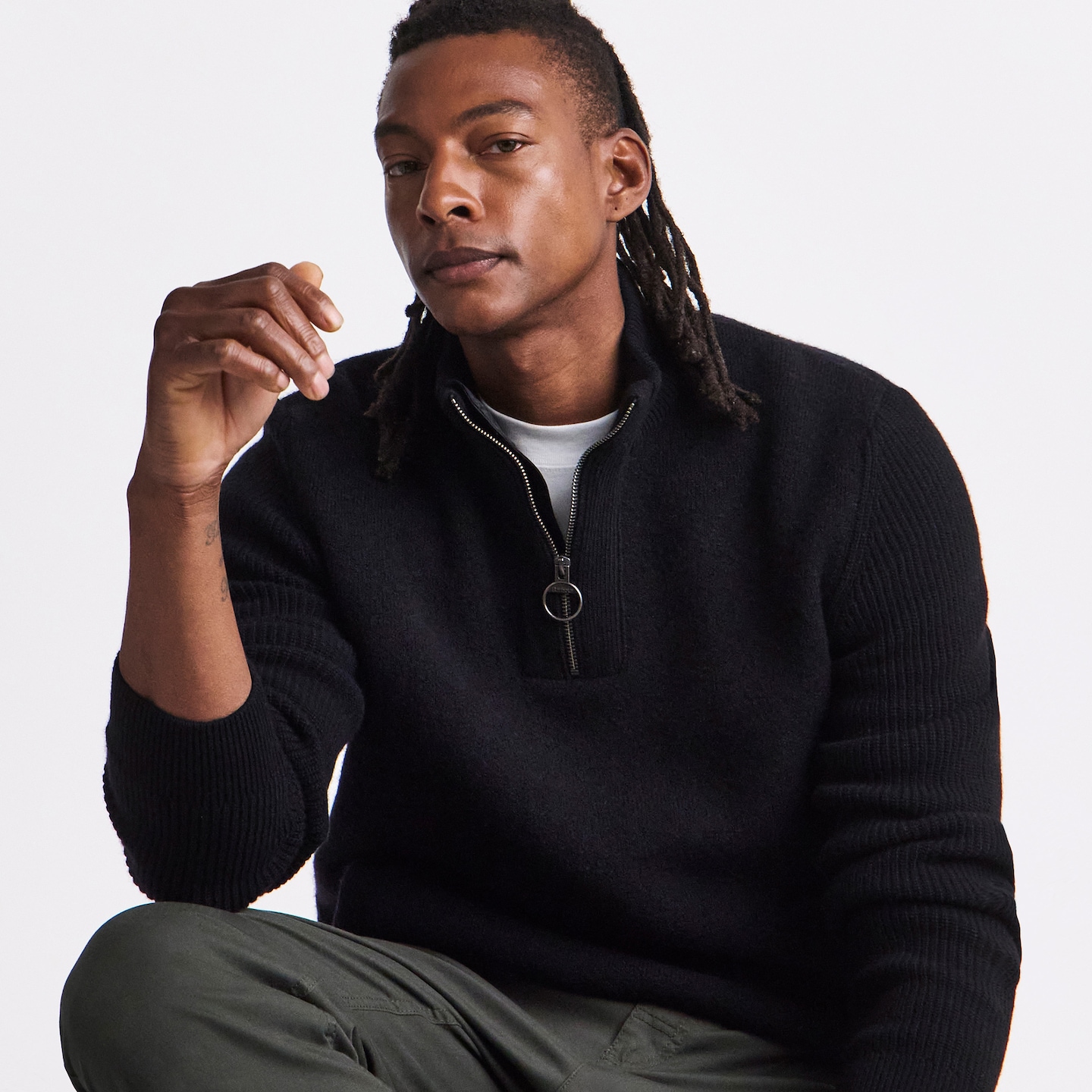 Model is wearing a black Barbour Milburn 1/2 zip knitted jumper with a pair of khaki trousers.