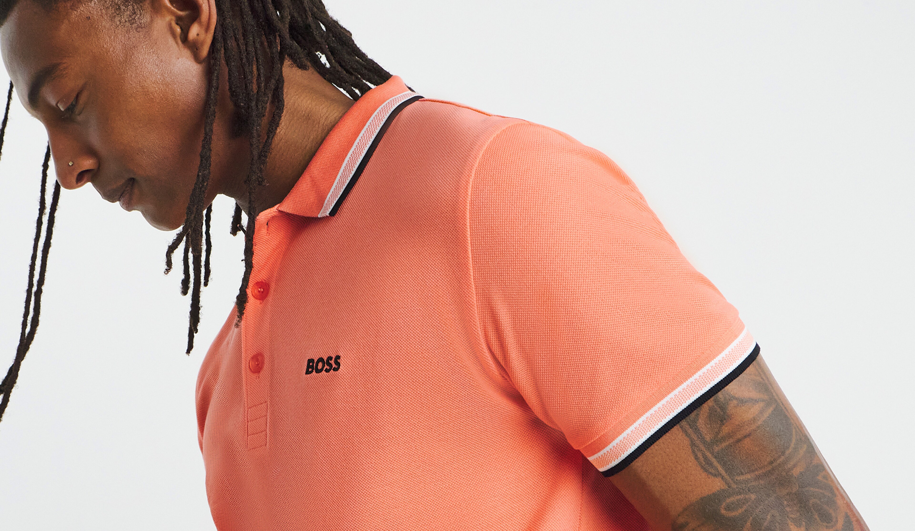 Model is wearing a coral BOSS short sleeve classic polo