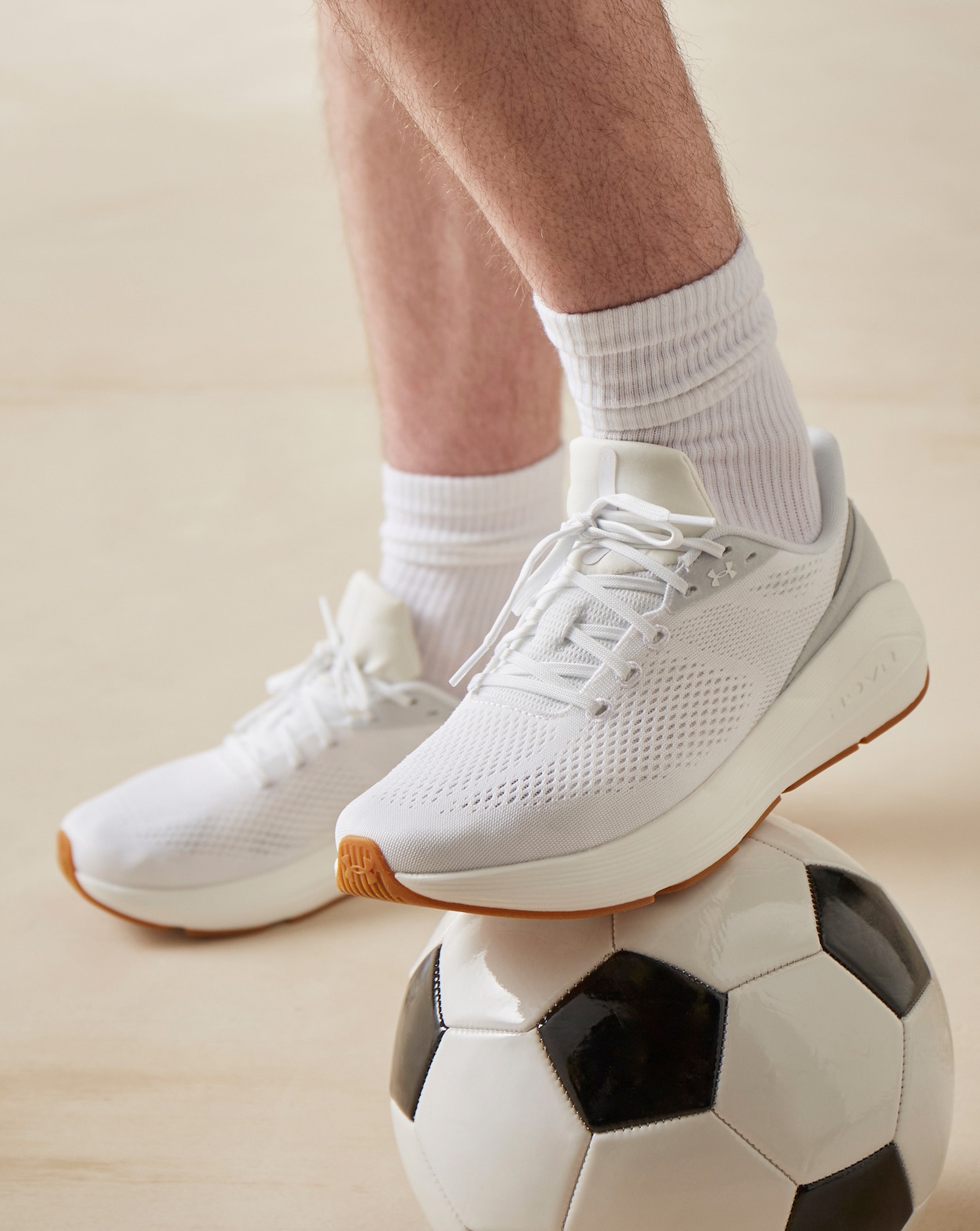 Model is wearing a pair of white Under Armour Sonic 7 trainers