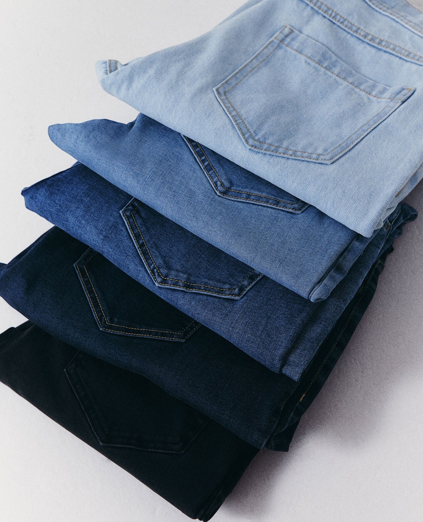 Folded jeans in a row different colour washes pictured