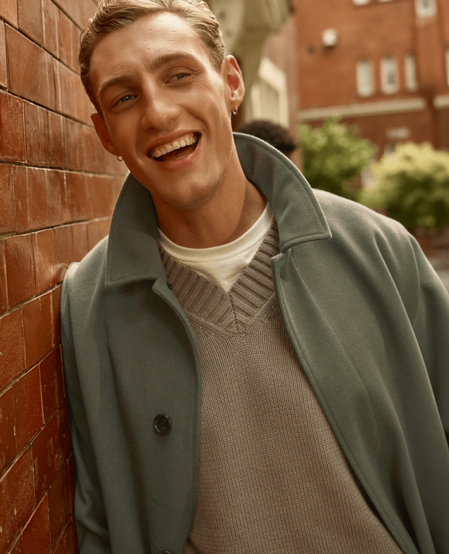 A man wearing an olive green jacket and beige jumper