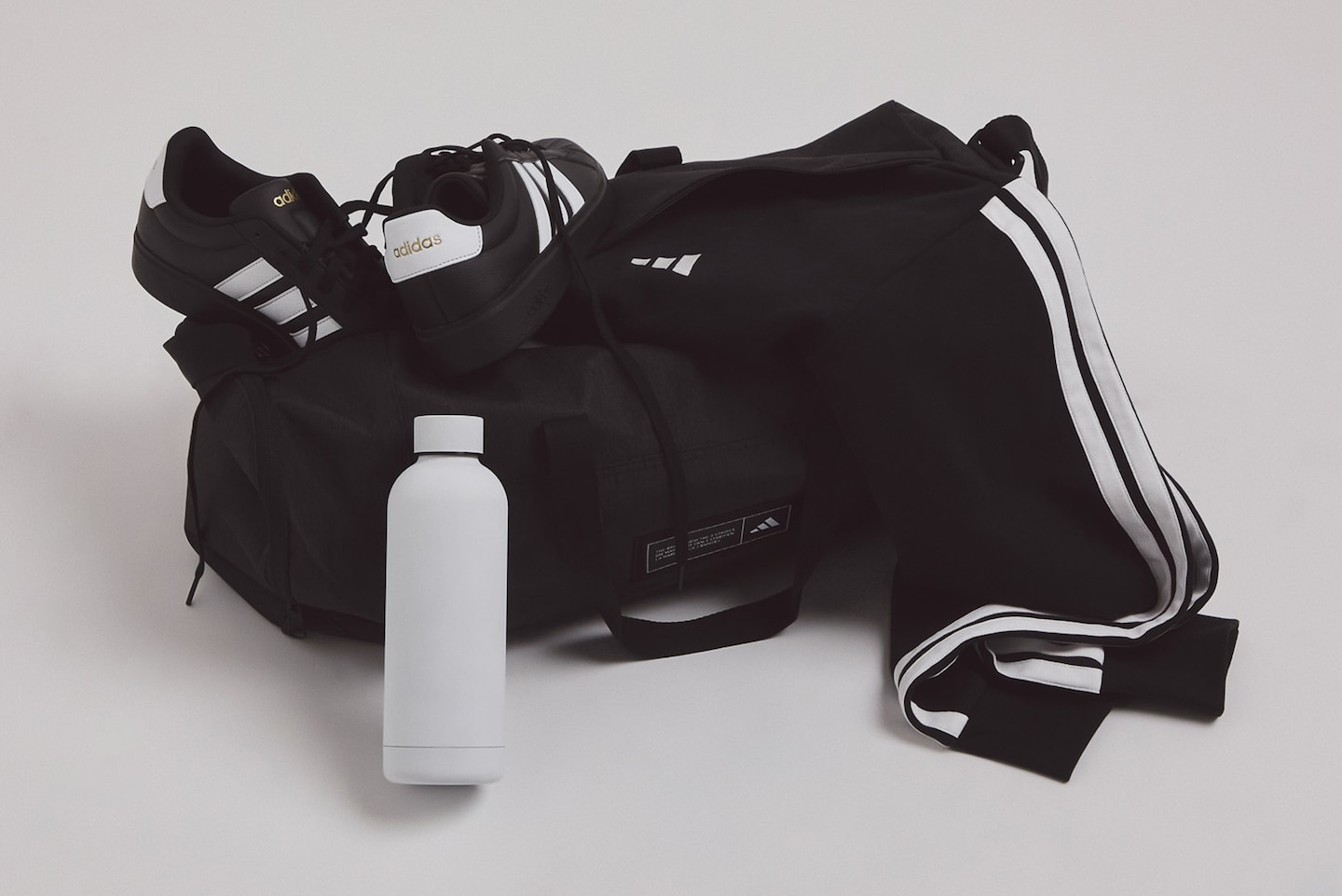 adidas gym bag is pictured with adidas 3 Stripes Full Zip Fleece joggers and adidas Streettalk Trainers
