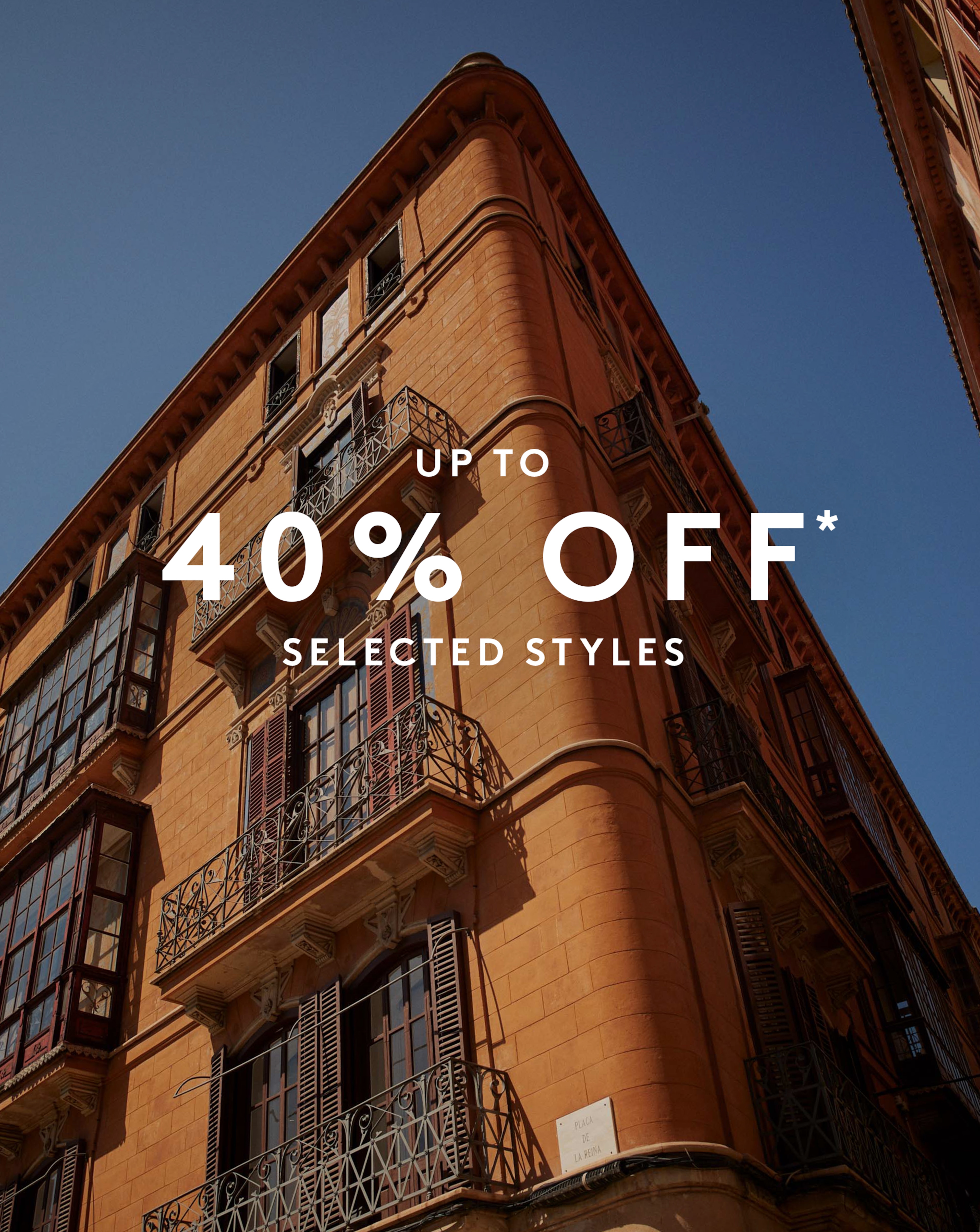 Up to 40% Off* Selected Styles. A building in a Spanish town is pictured with blue sky