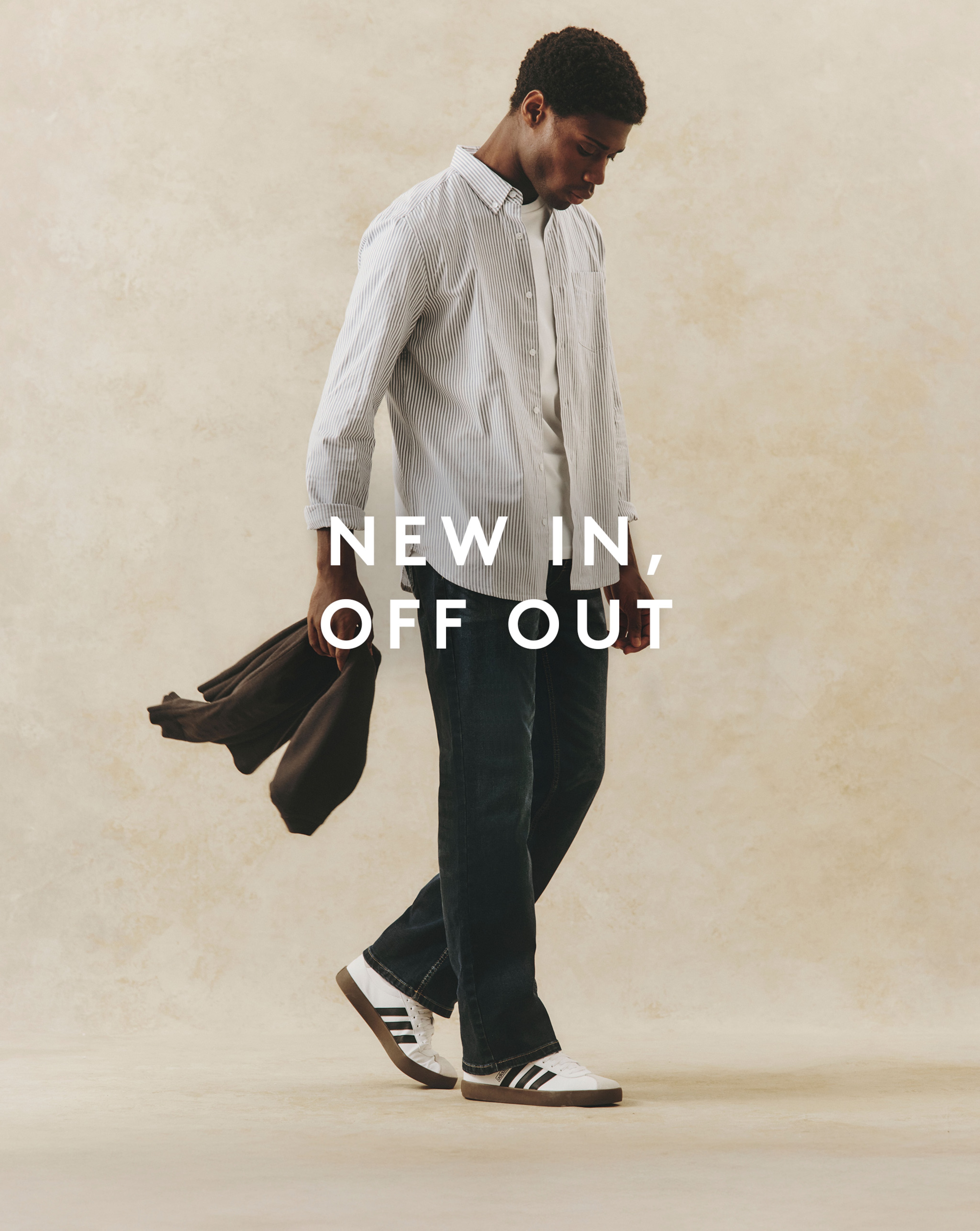 Model wearing a white striped shirt, jeans and adidas trainers
