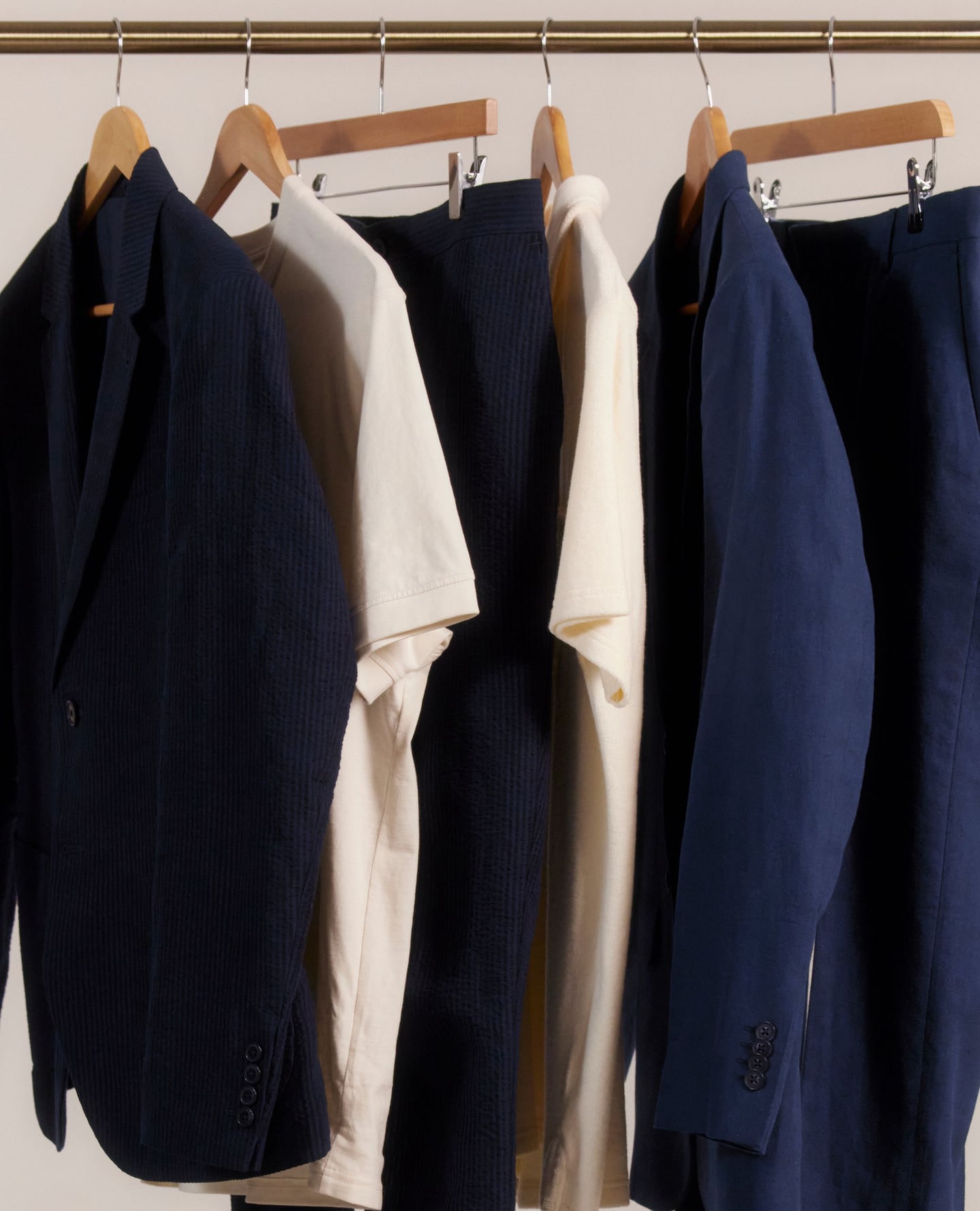 Navy suits, beige tops neatly hung up on a rail