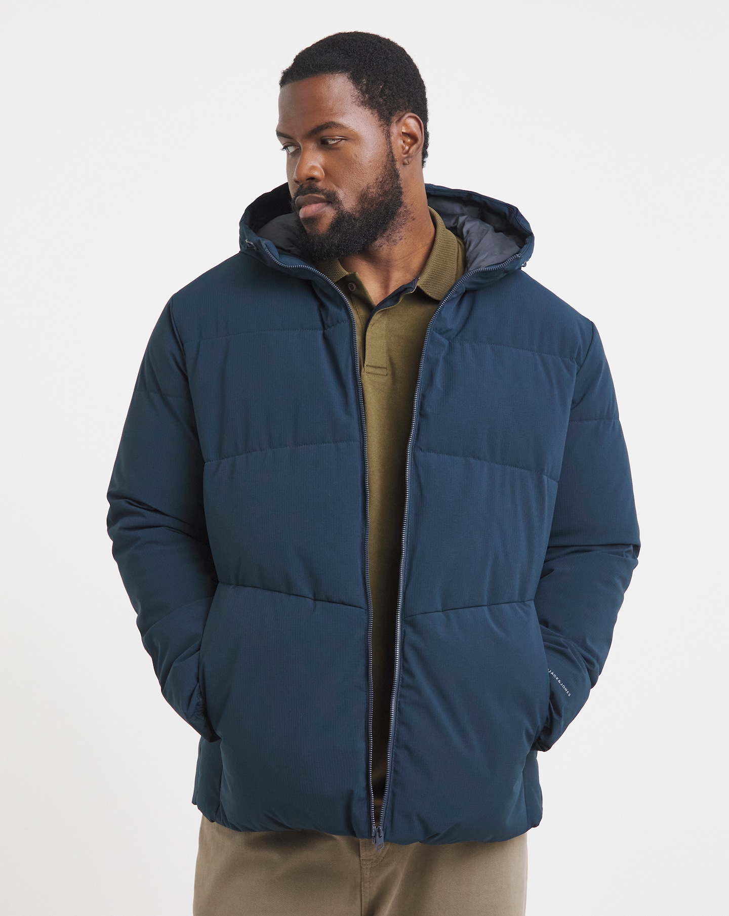 Man stood looking down to the left wearing a navy blue Jack & Jones puffer coat