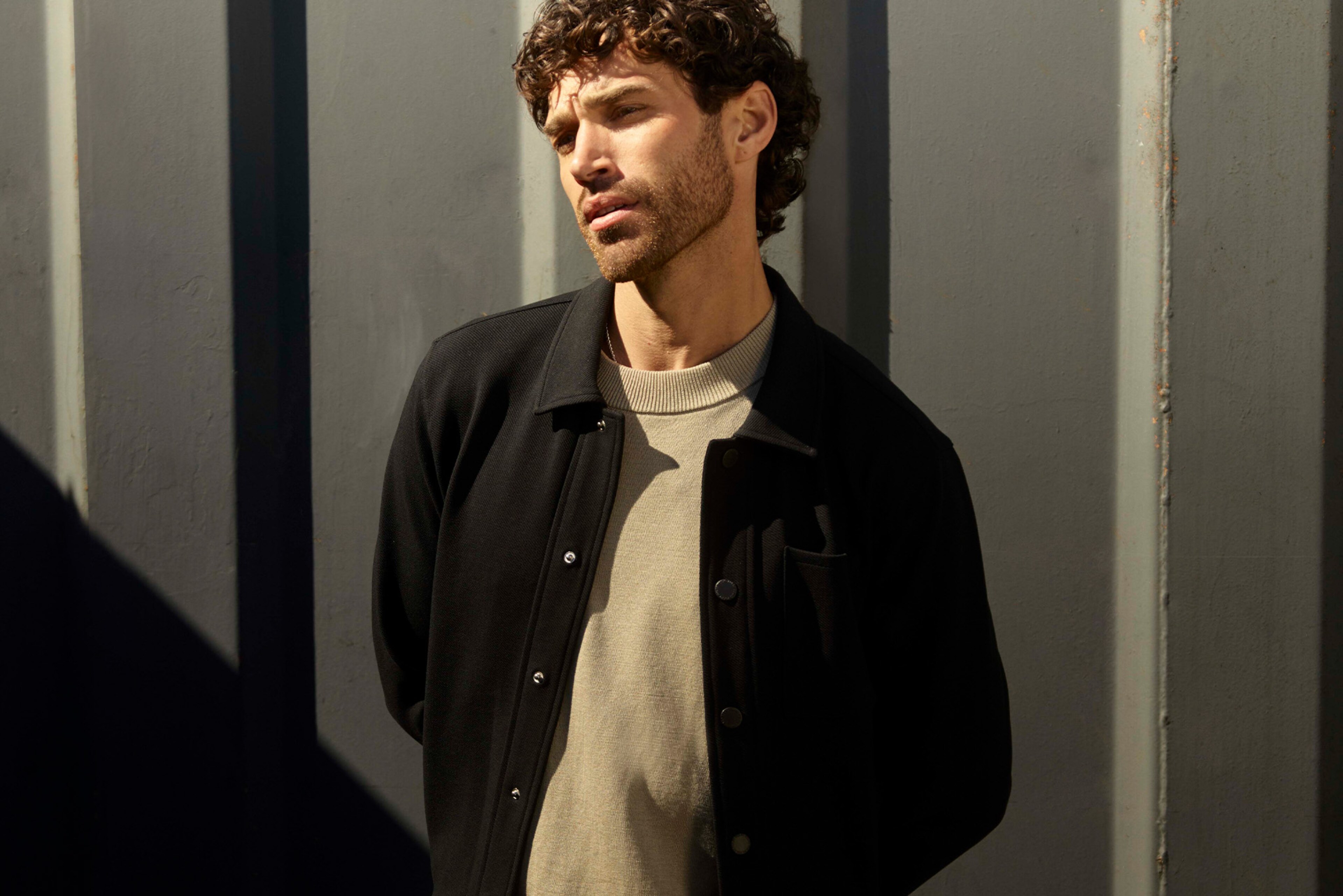 Model wearing black jacket and knitted jumper