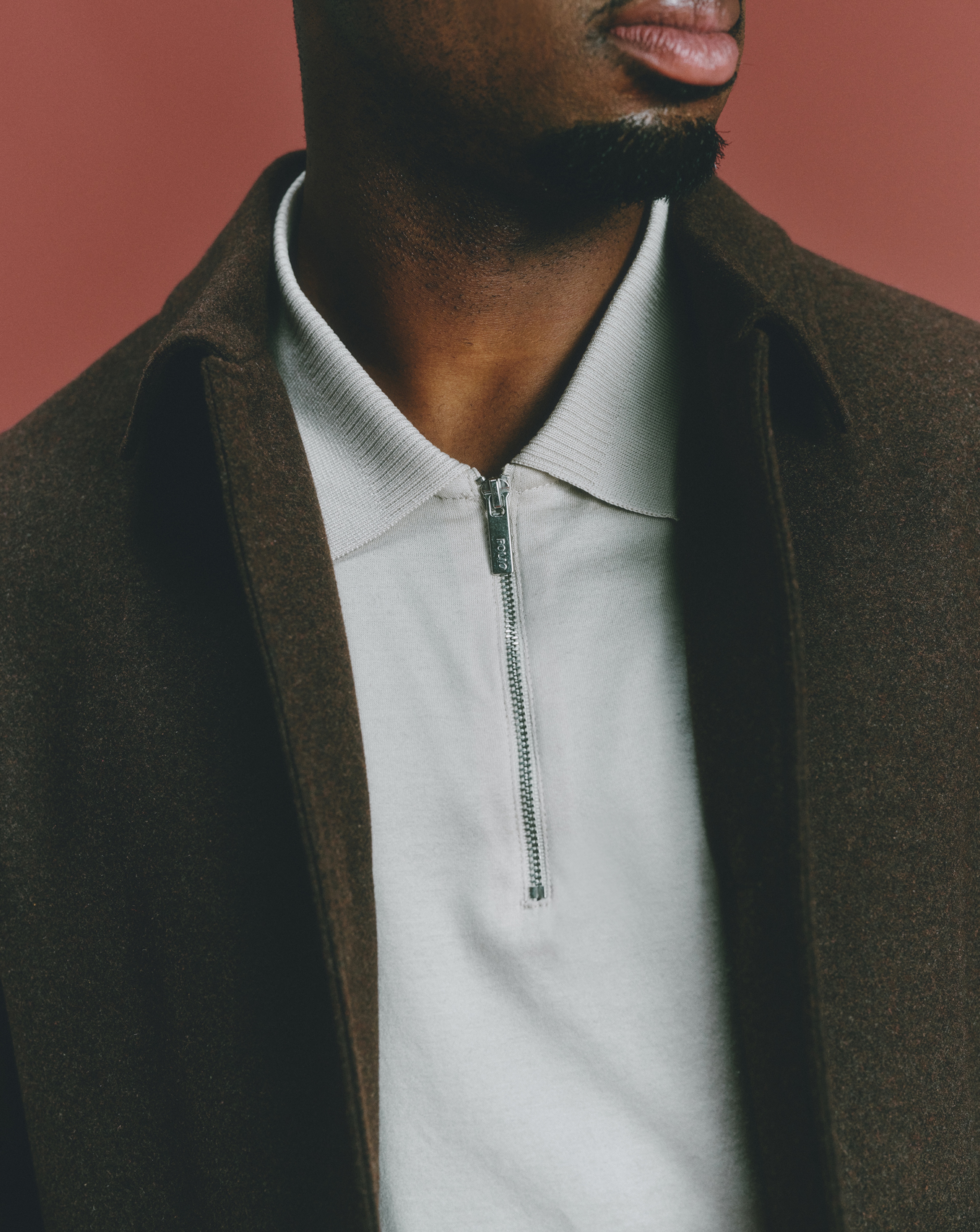 Going out. Model wears Tailored Tweed Button Through Jacket with Folio Mercerised Supima Zip Polo-Stone