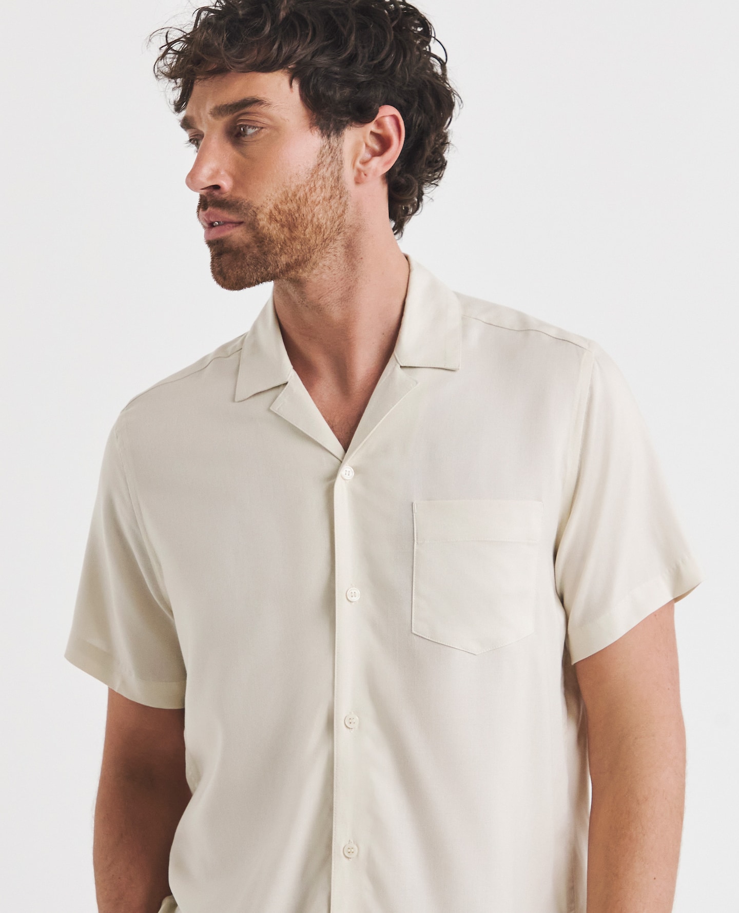 Model wearing button down cream, short-sleeved shirt