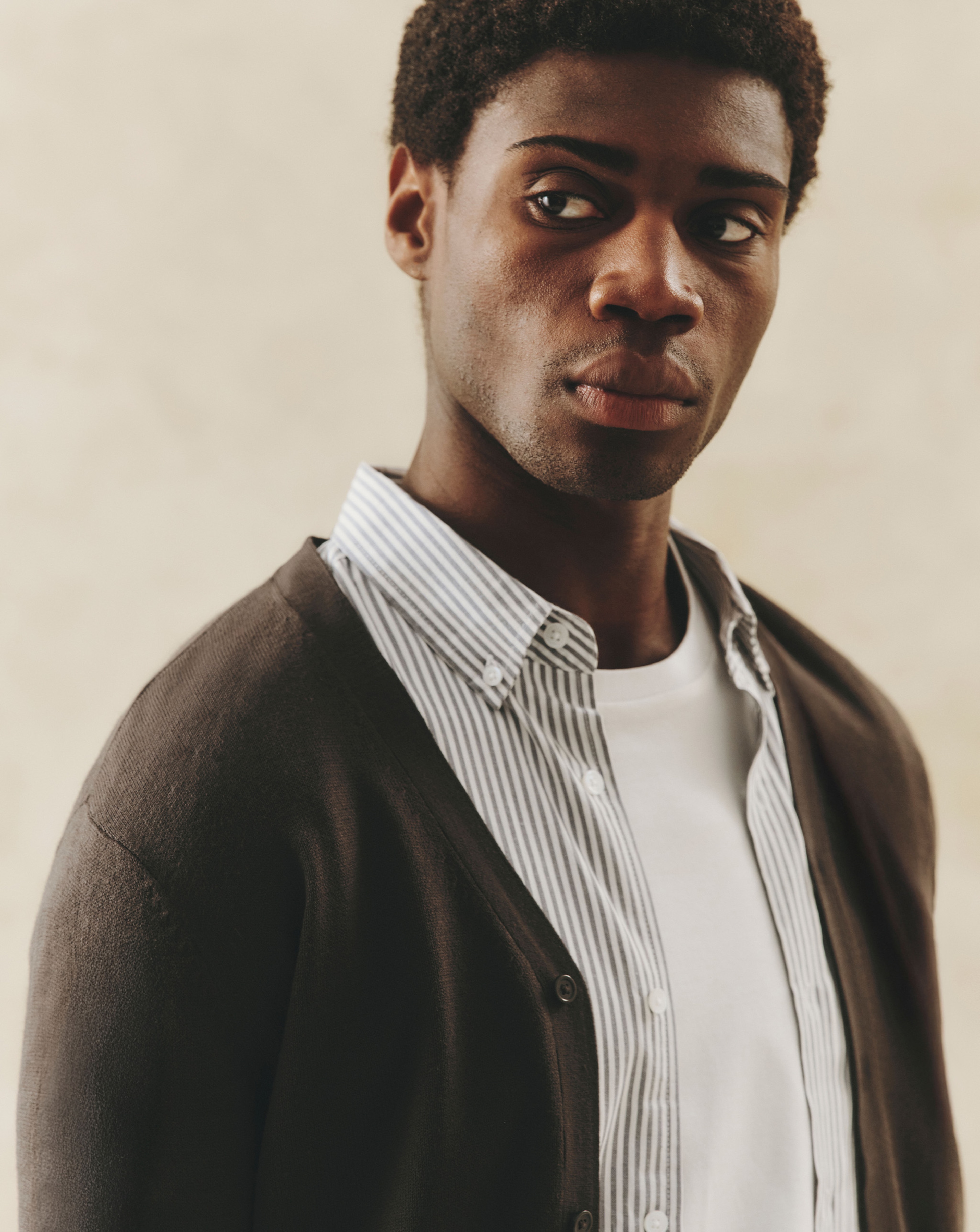 Model wearing a white t-shirt, layered with a blue shirt and brown cardigan
