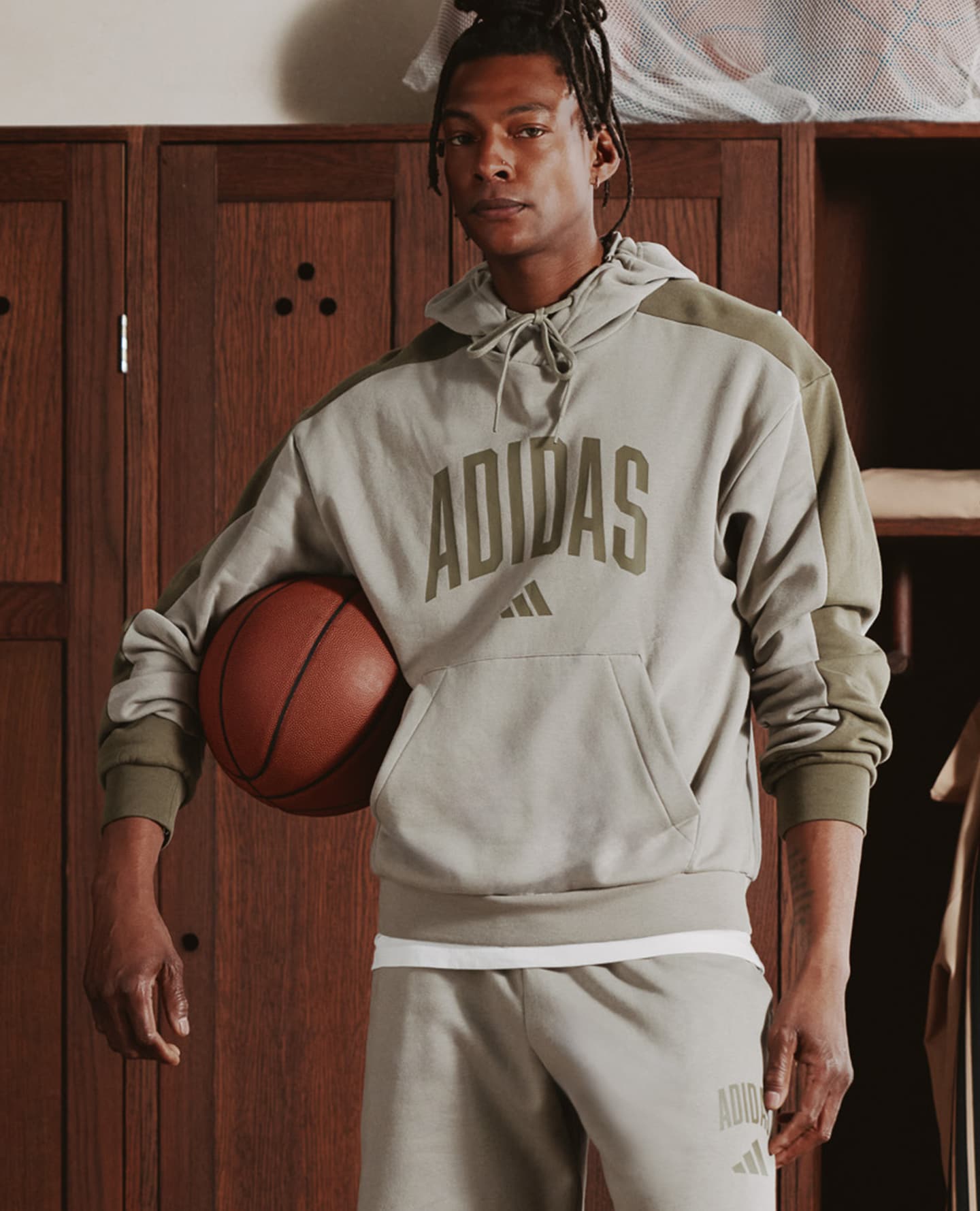 adidas Collegiate Logo Hoodie in Green is pictured with model holding basketball