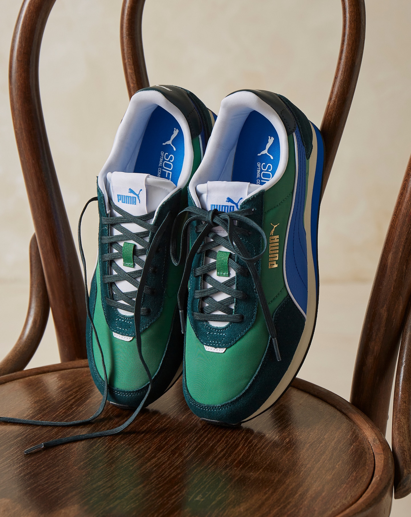 A pair of green multi-coloured PUMA St Miler Rise trainers on a brown chair