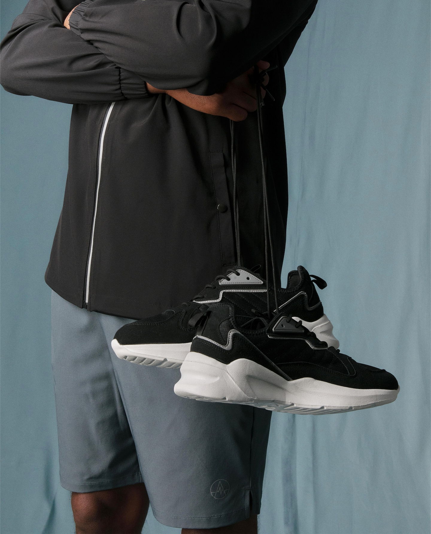 A man stood holding a pair of black trainers