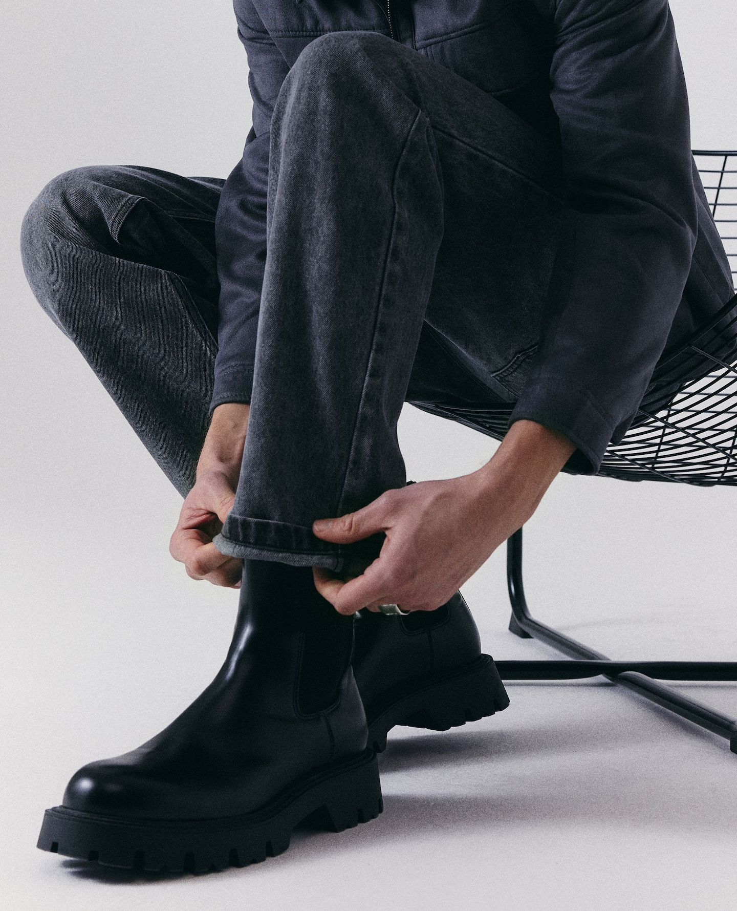 Model sat pulls down leg of straight fit jeans