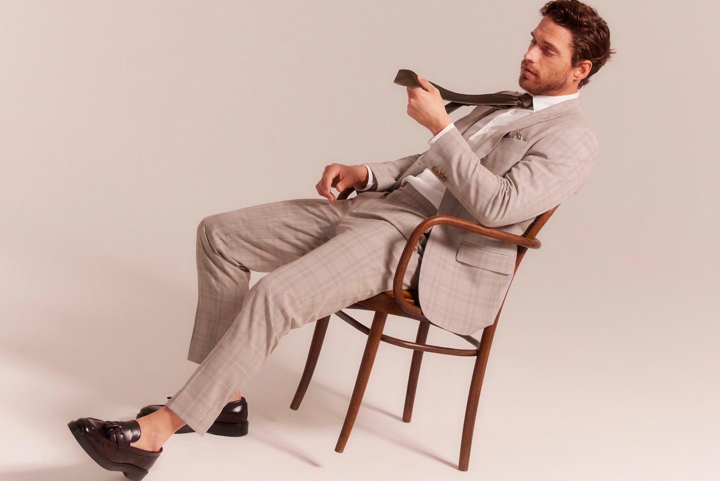 A man sat in a chair wearing a beige suit