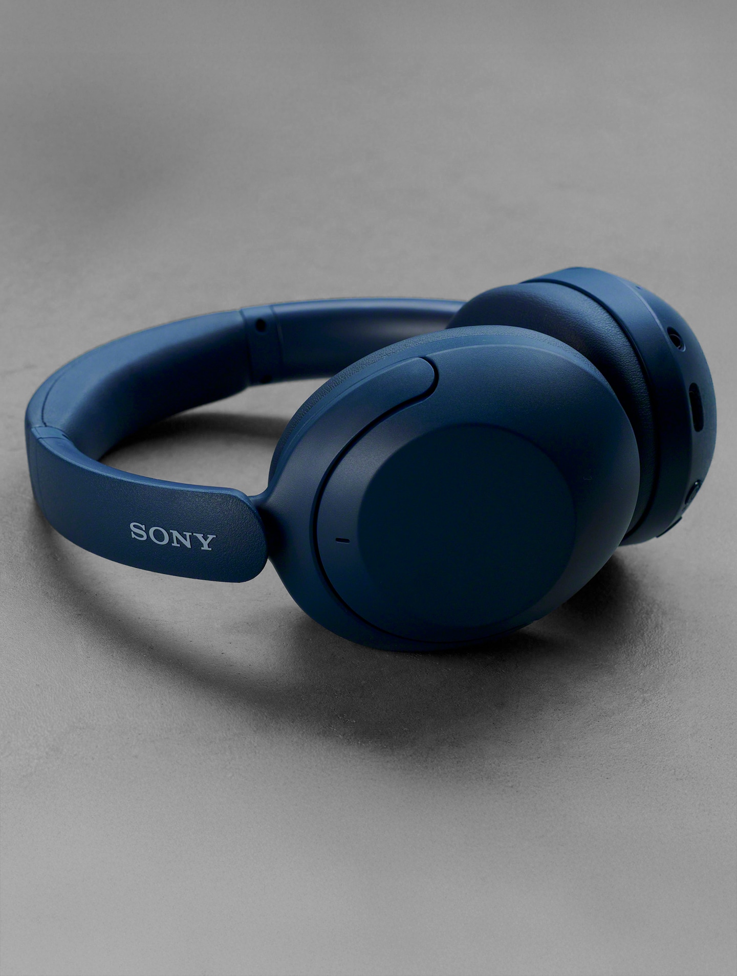 Blue Sony wireless headphones on a grey surface