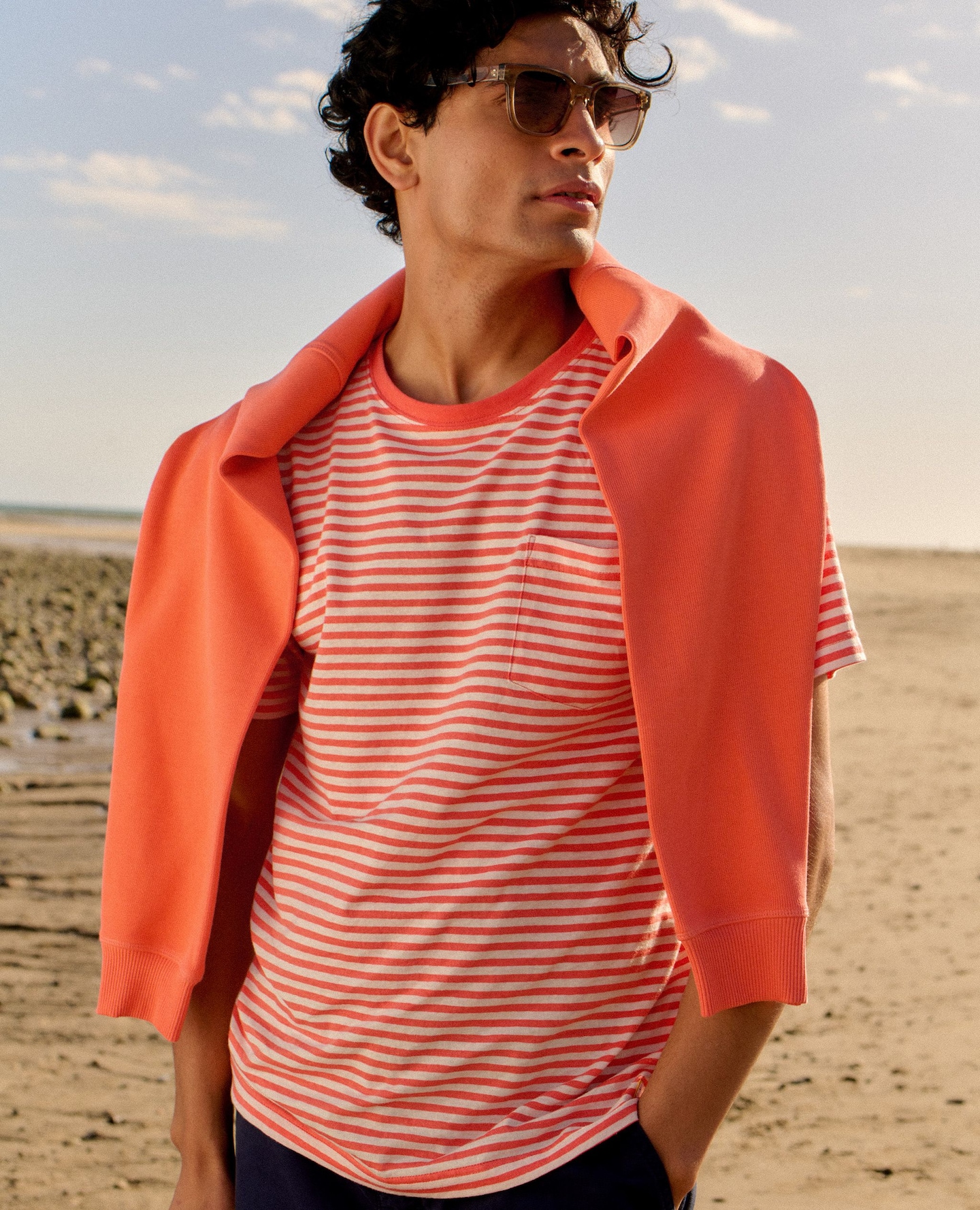 Model on a beach wearing a salmon striped T-Shirt