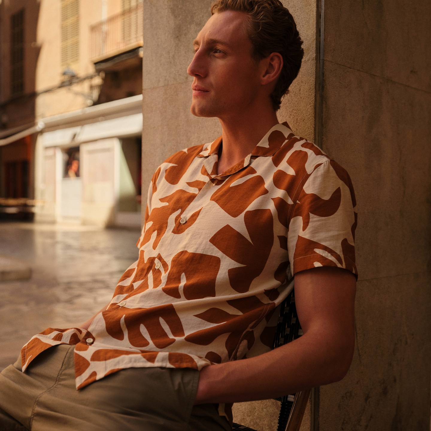 Model sat wearing a patterned orange and cream shirt