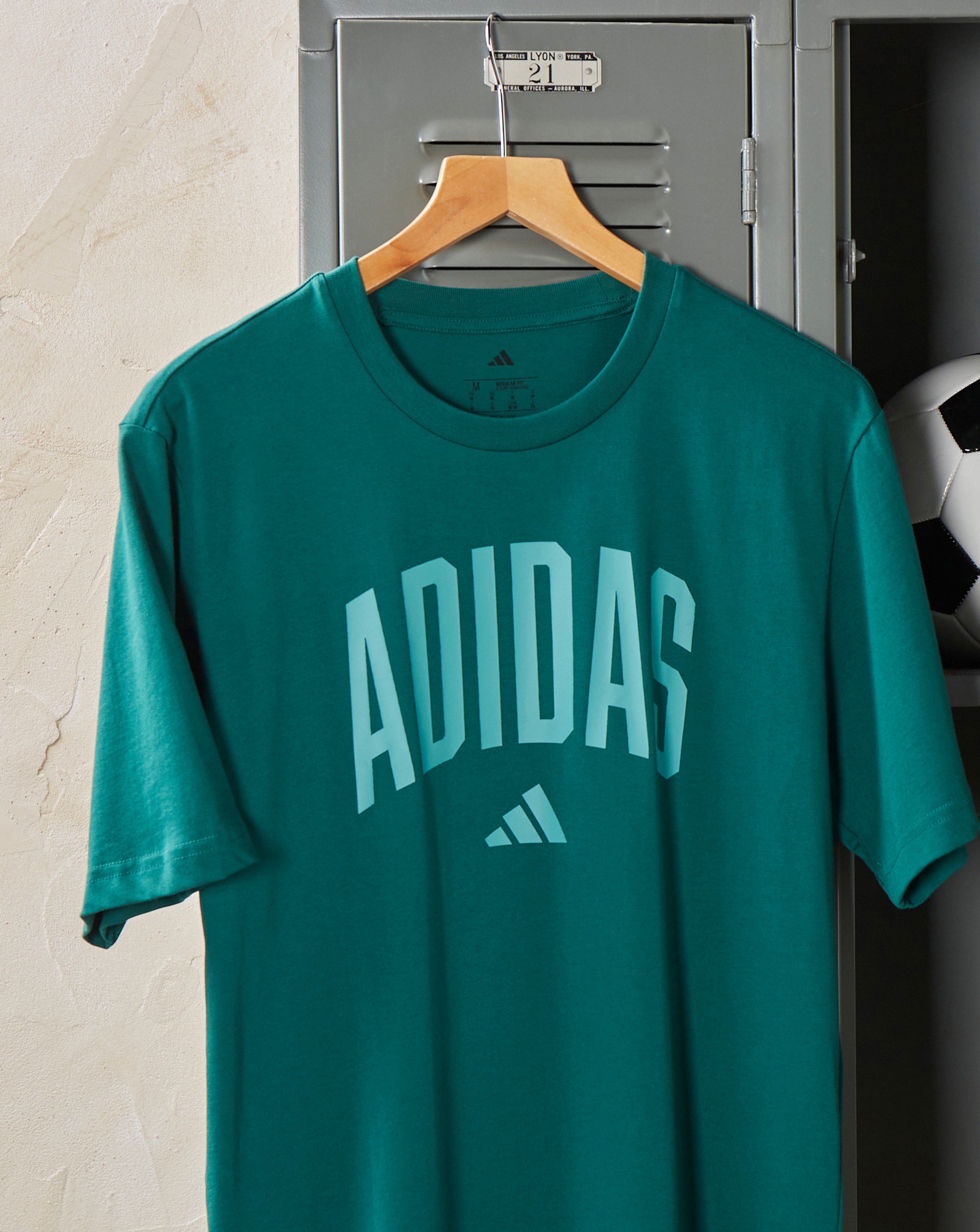 Green adidas t-shirt hung on locker