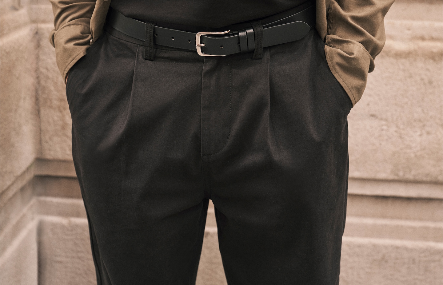 Model wears pleated trousers in black