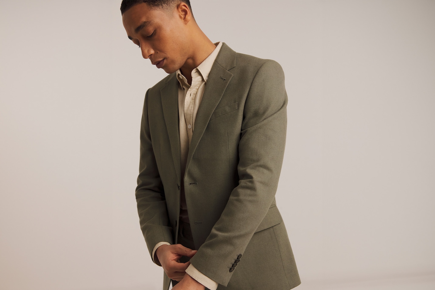 Model wearing green blazer and cream shirt