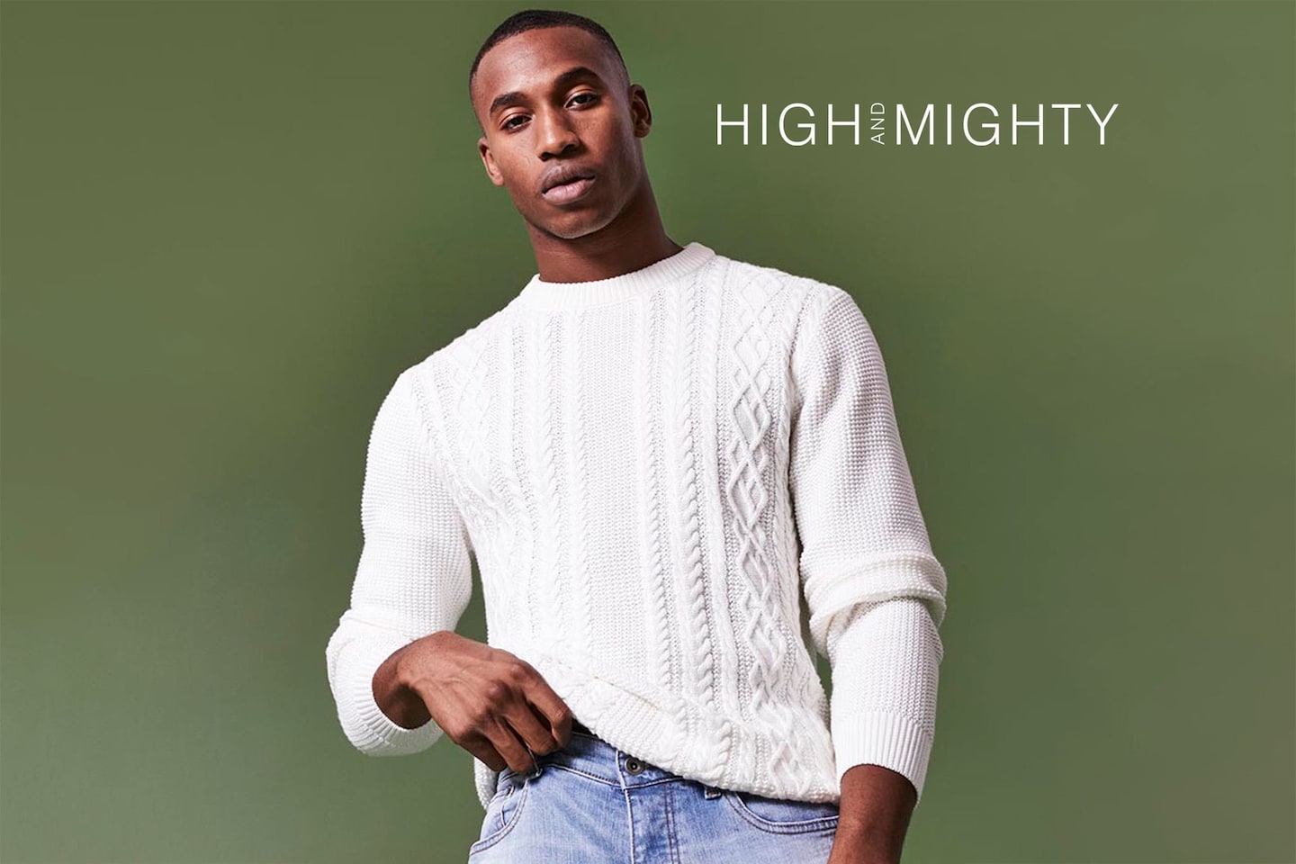 Model wearing white knit jumper and blue denim jeans - High & Mighty logo