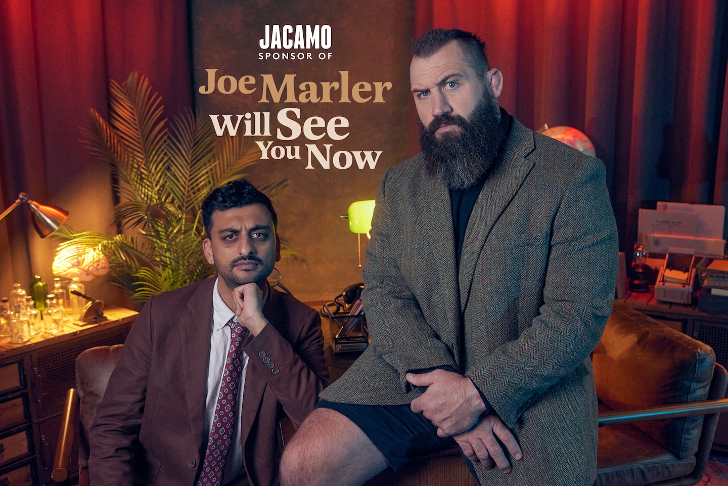 Jacamo sponsor of Joe Marler Will See You Now. Joe Marler sat on desk in Tweed Blazer with presenter
