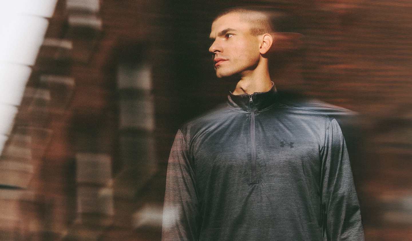 Image shows a runner against an urban backdrop wearing Under Armour sports