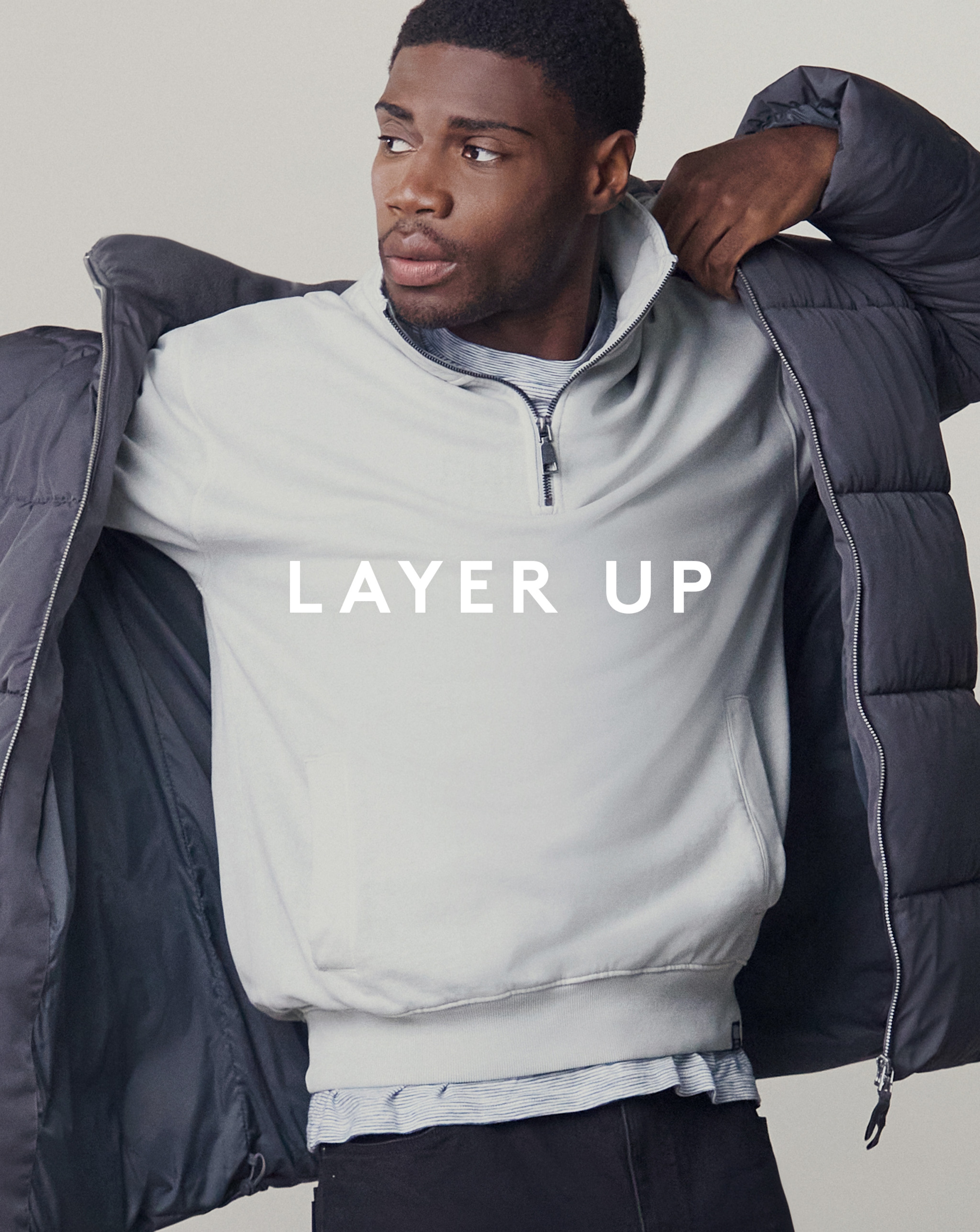 Model wearing a 1/4 grey zip sweater and a grey puffer jacket