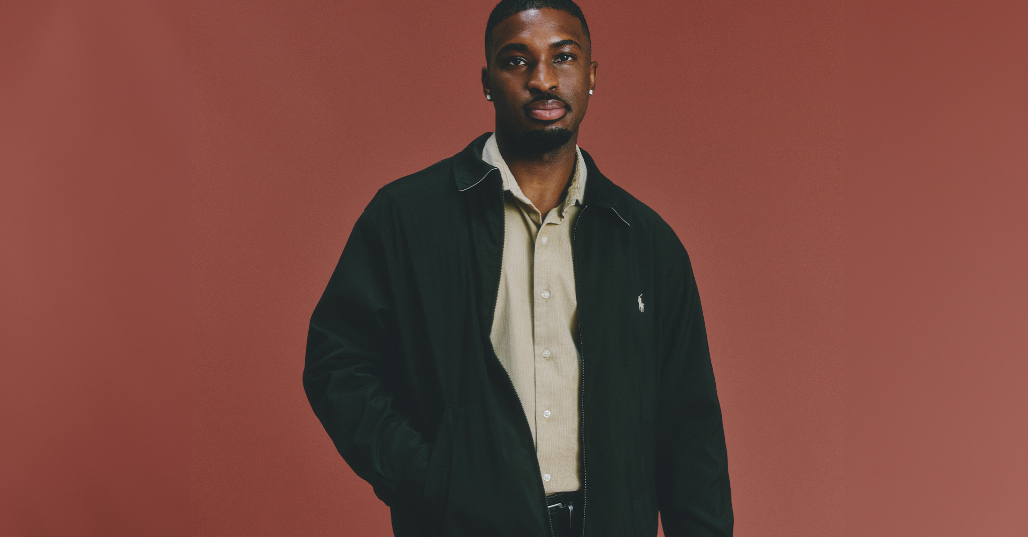 Model wearing Polo Ralph Lauren jacket against a red, festive background