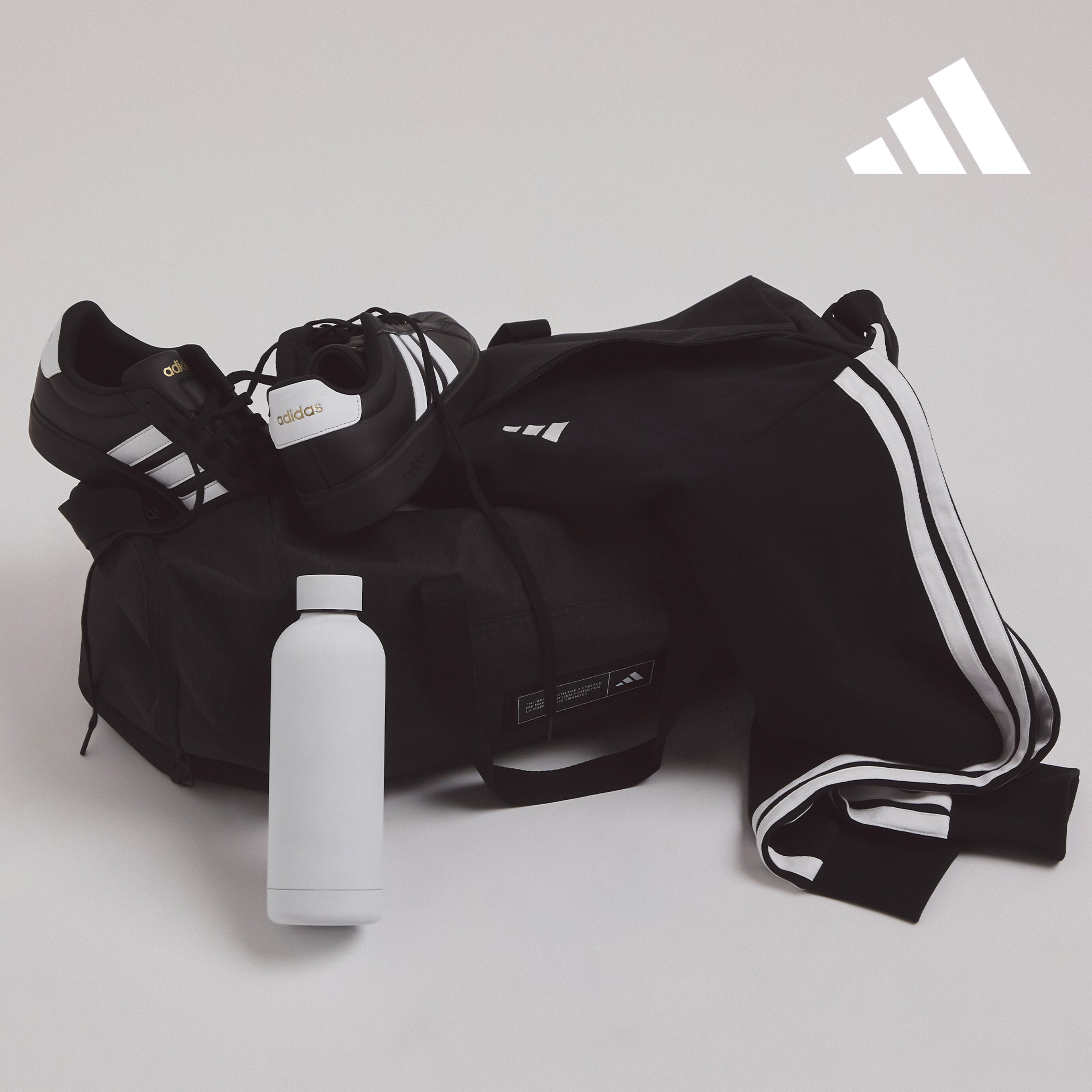 black adidas tracksuit and trainers inside an adidas sports bag