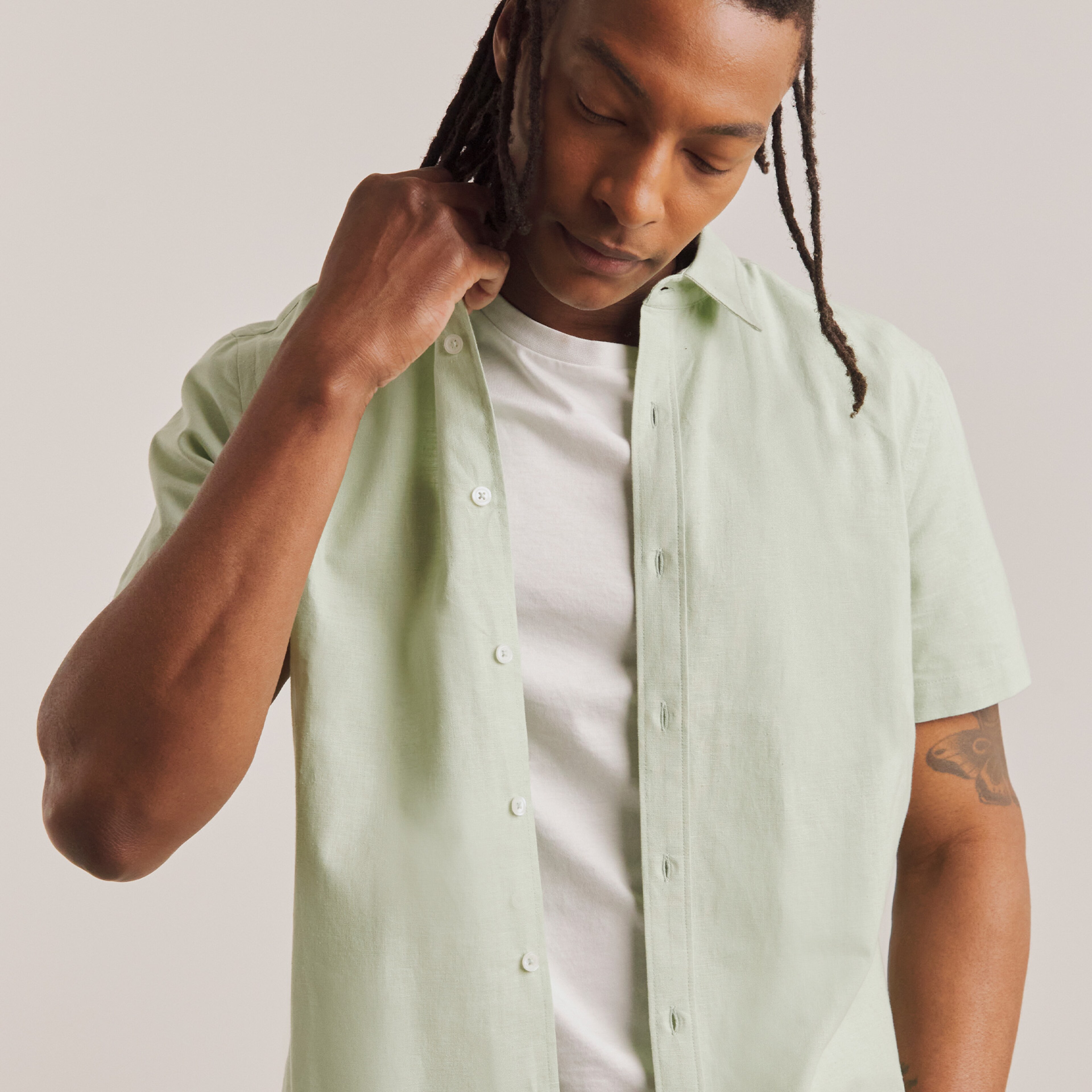 Model wearing white t-shirt with a light green button up shirt layered on top